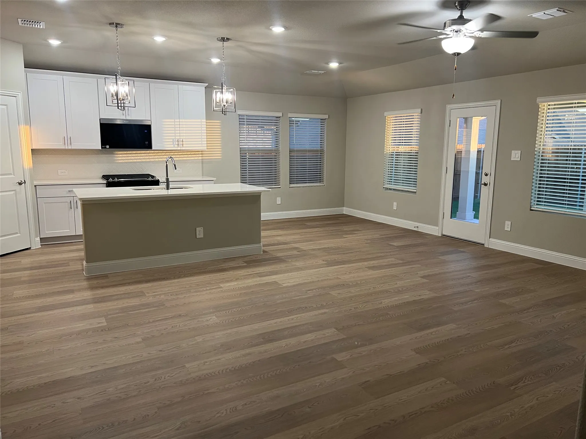 Expansive open-concept living area featuring wood-finish flooring, recessed lighting, and a ceiling fan