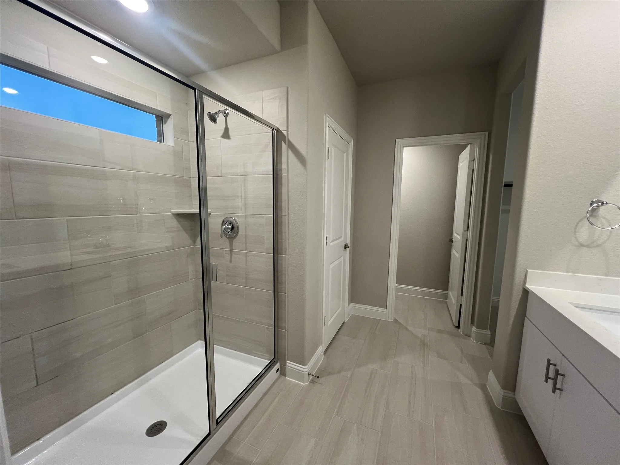 Full walk-in shower with glass enclosure, chrome fixtures, and horizontal tile surround