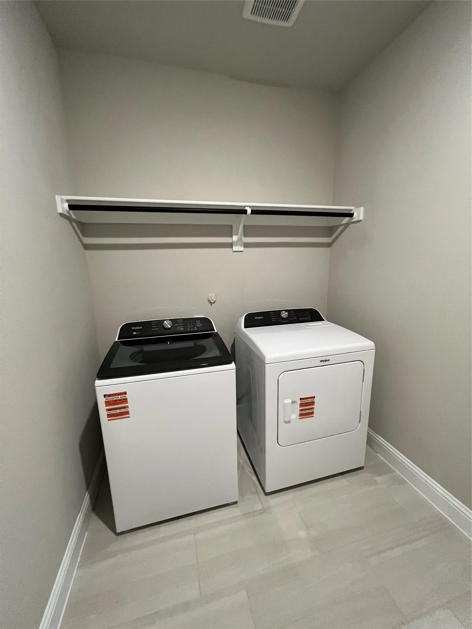 Laundry area featuring a built-in shelf with a hanging rod and tile flooring