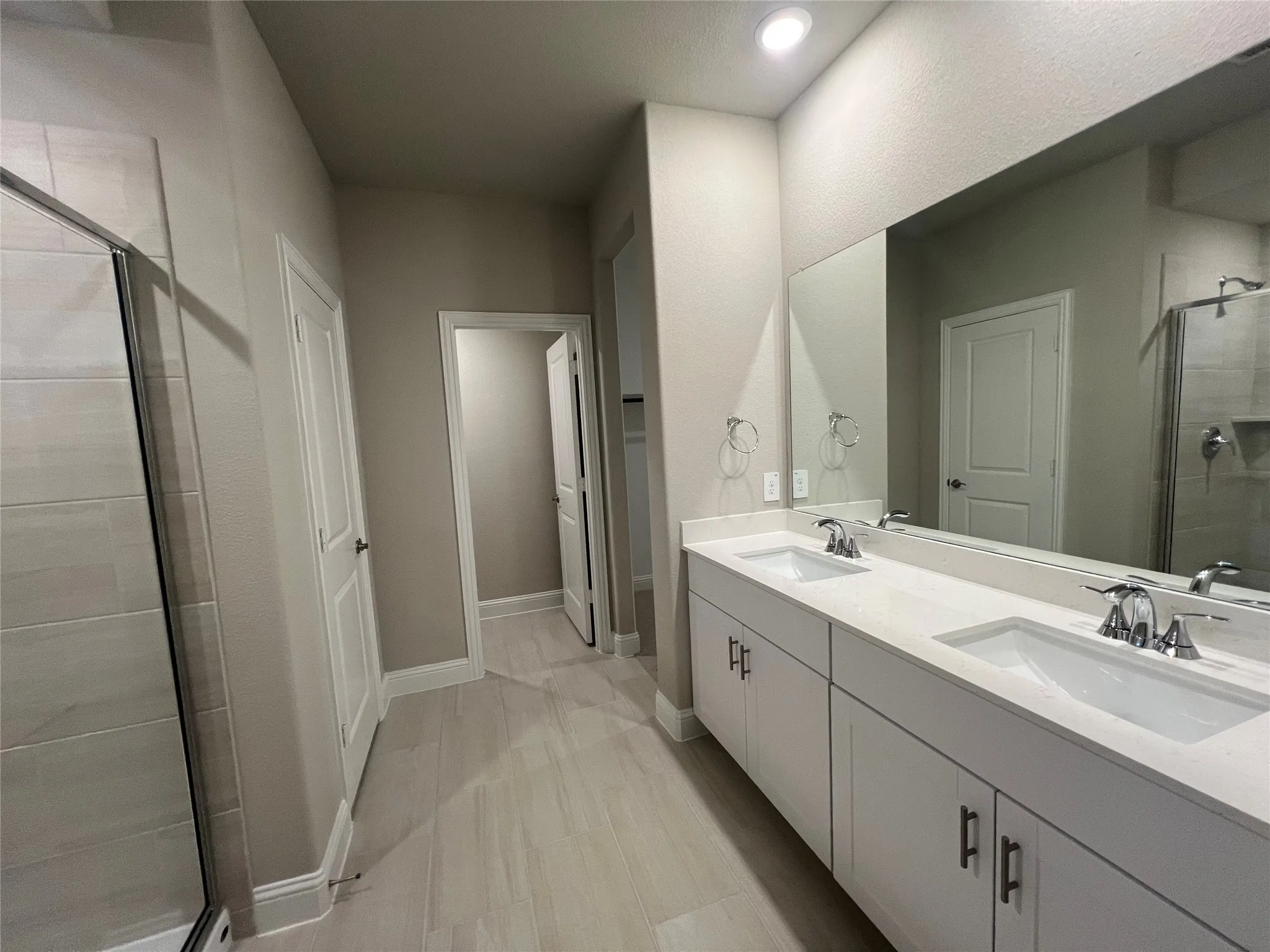 Double vanity with white cabinetry, integrated sinks, and polished chrome fixtures
