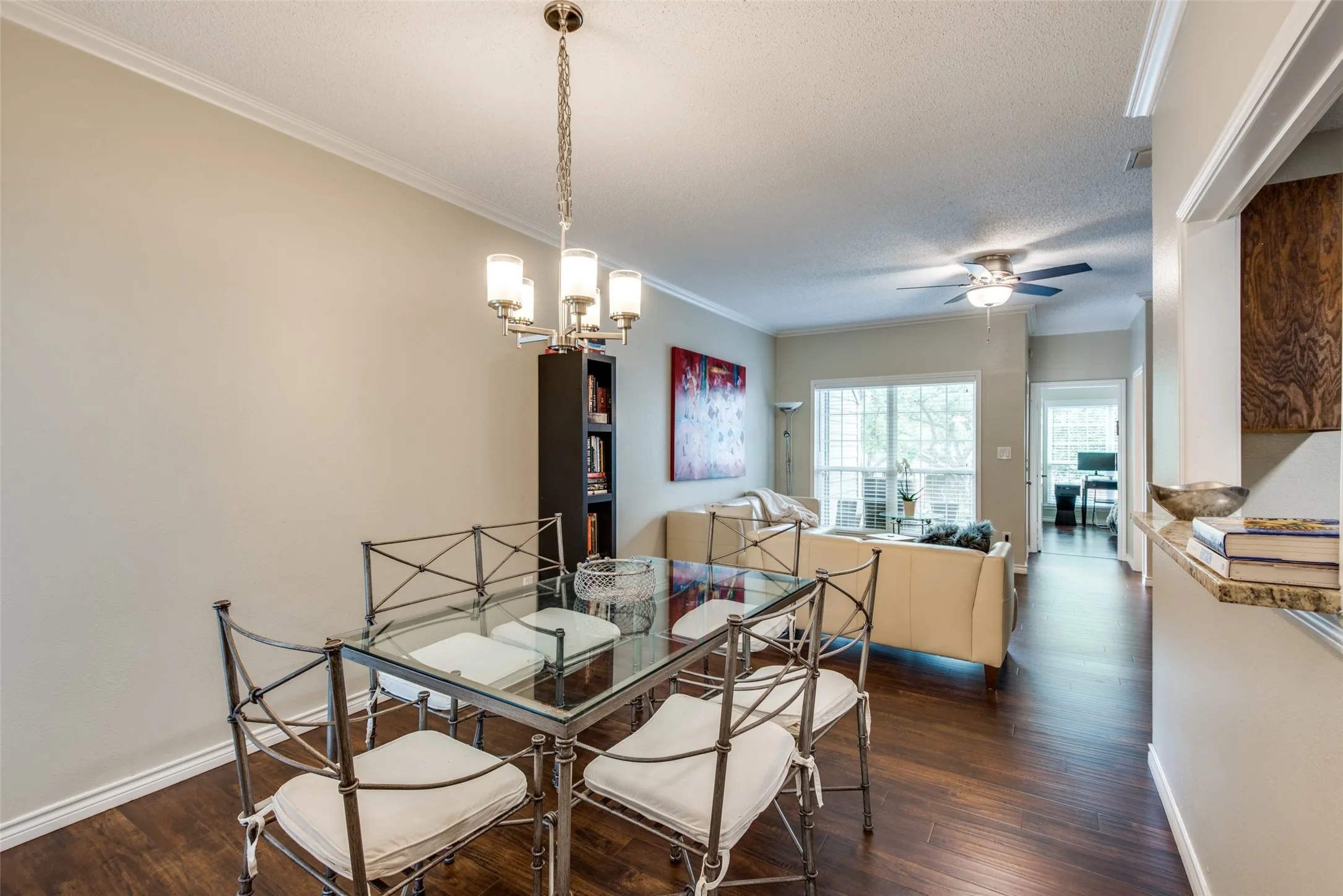 Dark wood-finish flooring, crown molding, and a chandelier with brushed nickel accents