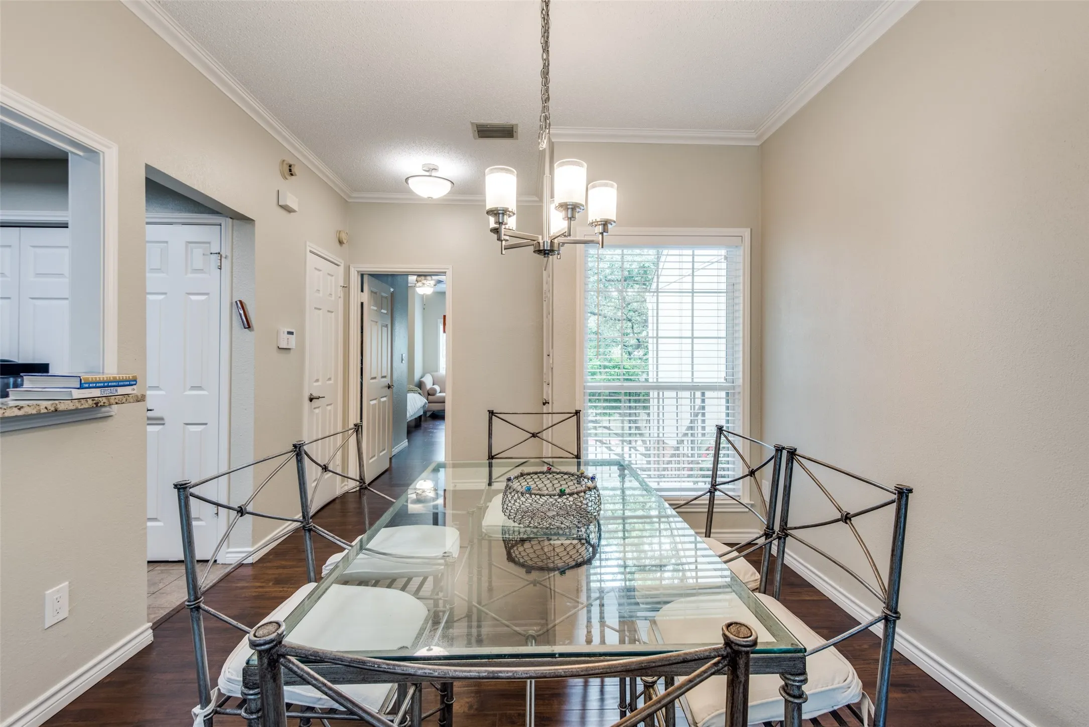 Dining area featuring wood-finish flooring, crown molding, and a multi-light chandelier