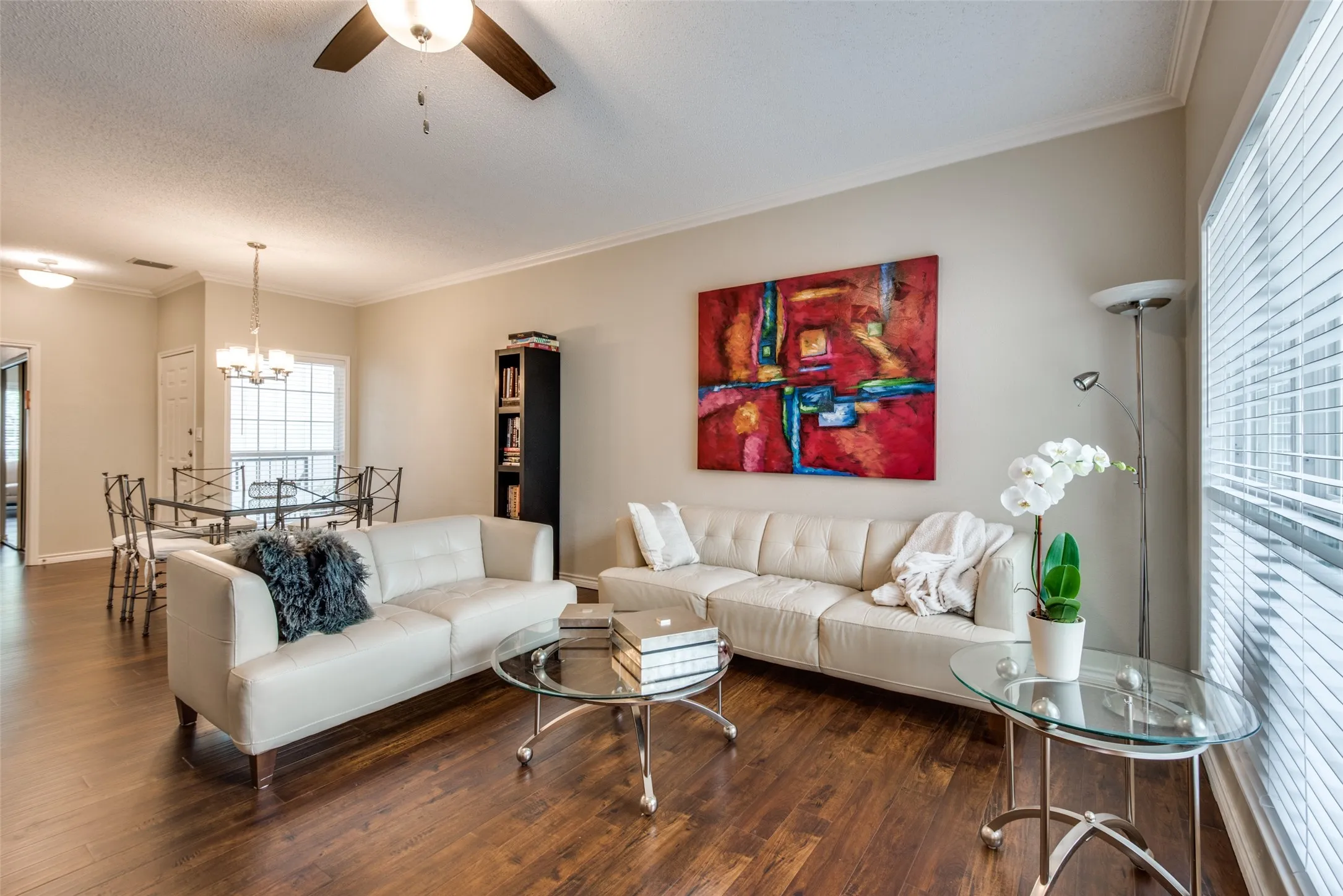 Wood-finish flooring throughout, crown molding, built-in shelving, and a ceiling fan with integrated lighting