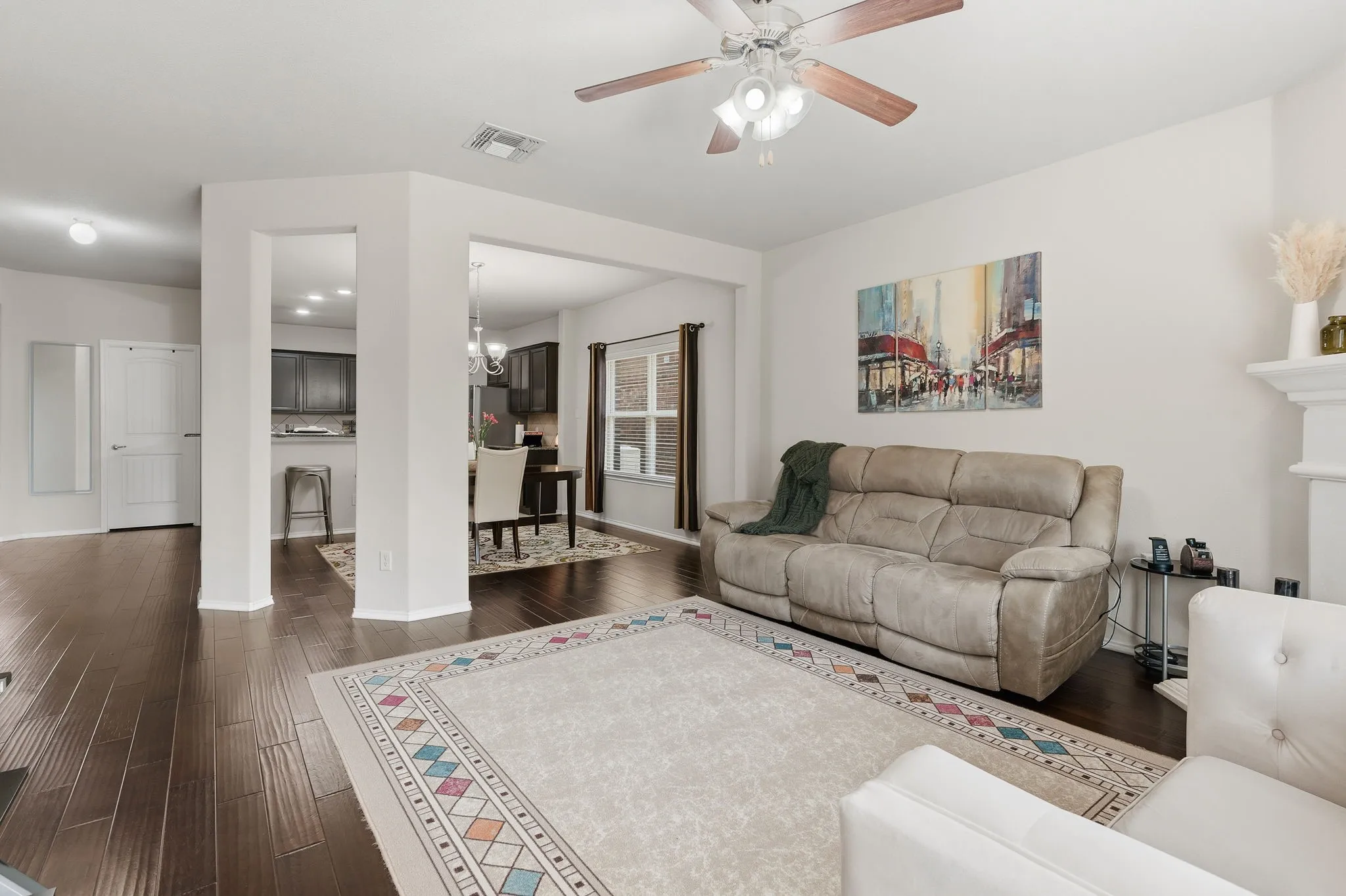 Wood-finish flooring throughout, ceiling fan with light fixture, fireplace mantel, and recessed lighting