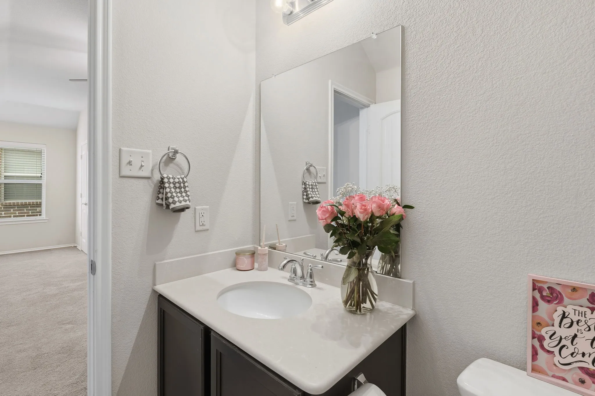 Vanity with an integrated sink and light-toned countertop, framed by a wall-mounted mirror