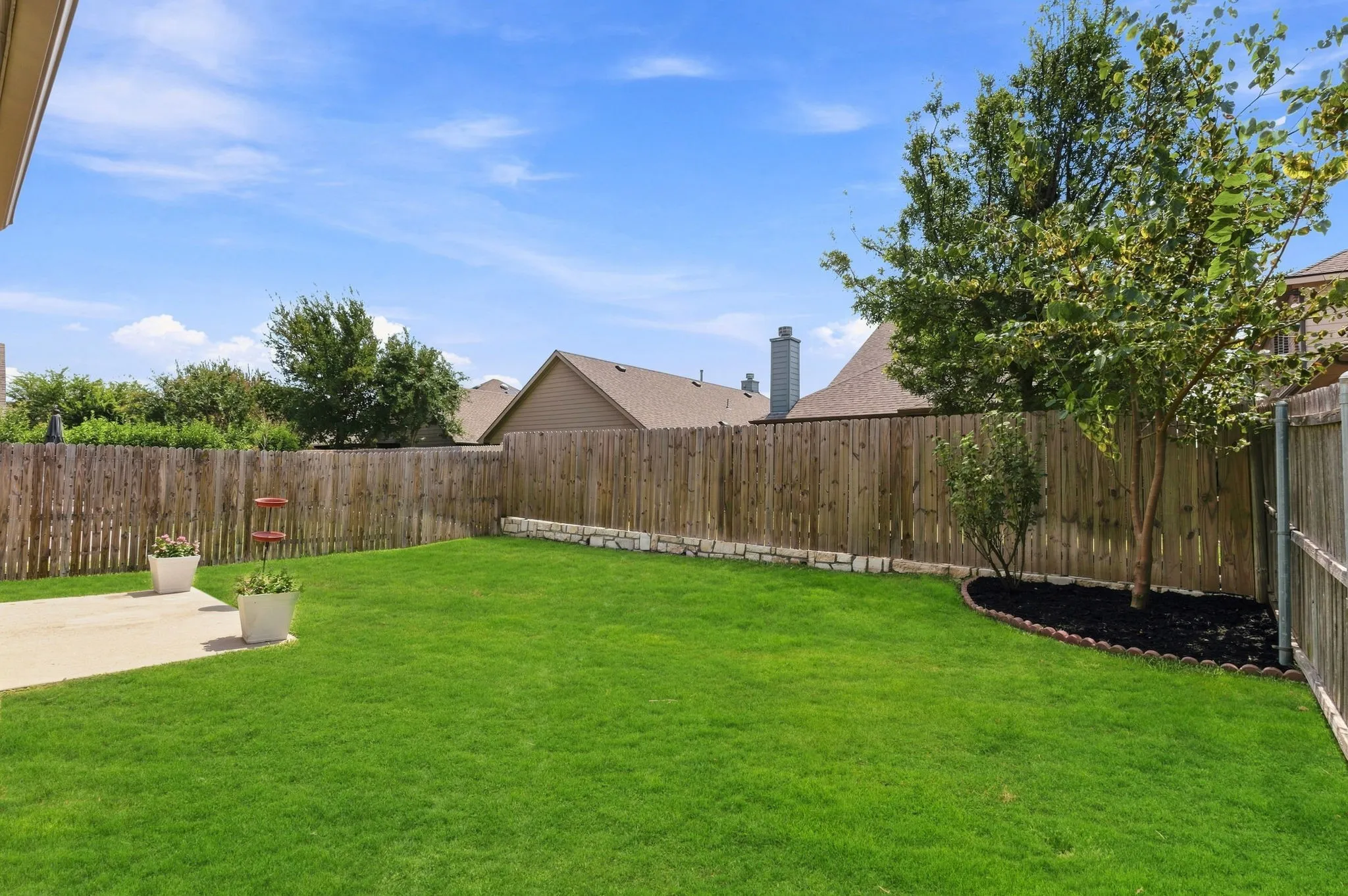 Expansive backyard featuring a lush lawn, concrete patio, and a wood privacy fence