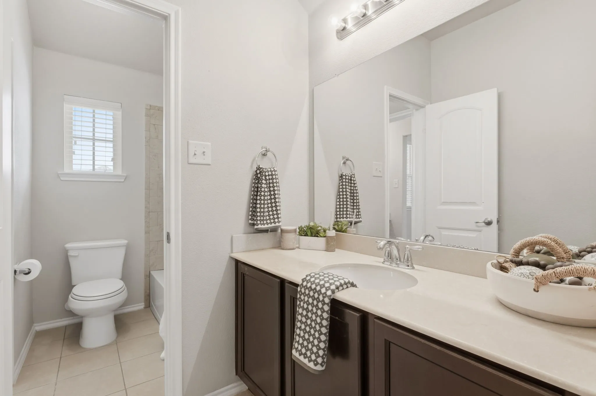 Vanity with an integrated sink and chrome faucet, dark wood-finish cabinetry, and a large wall-mounted mirror