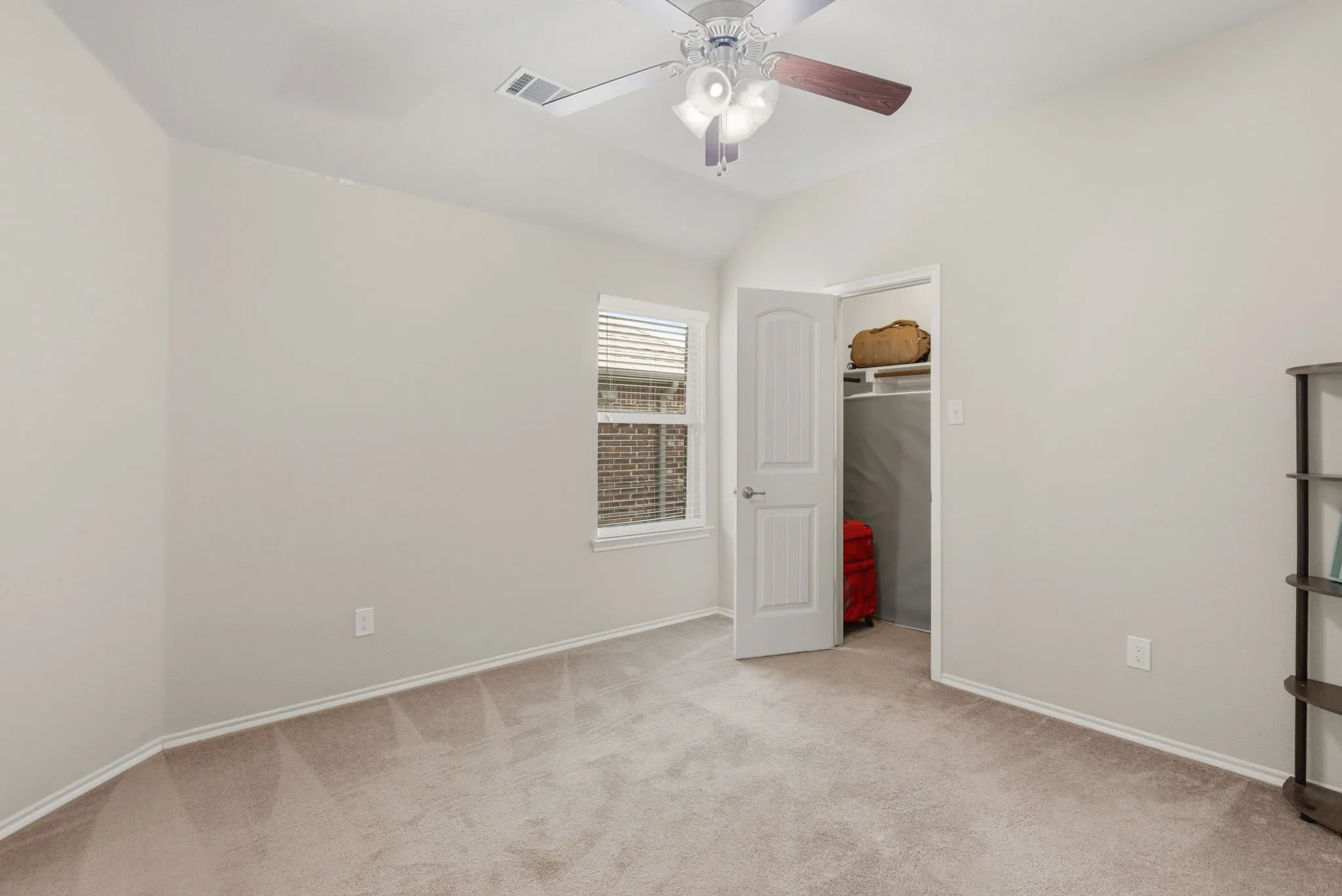 Carpeted room featuring a window with blinds, a ceiling fan with integrated lighting, and a closet with a built-in shelf