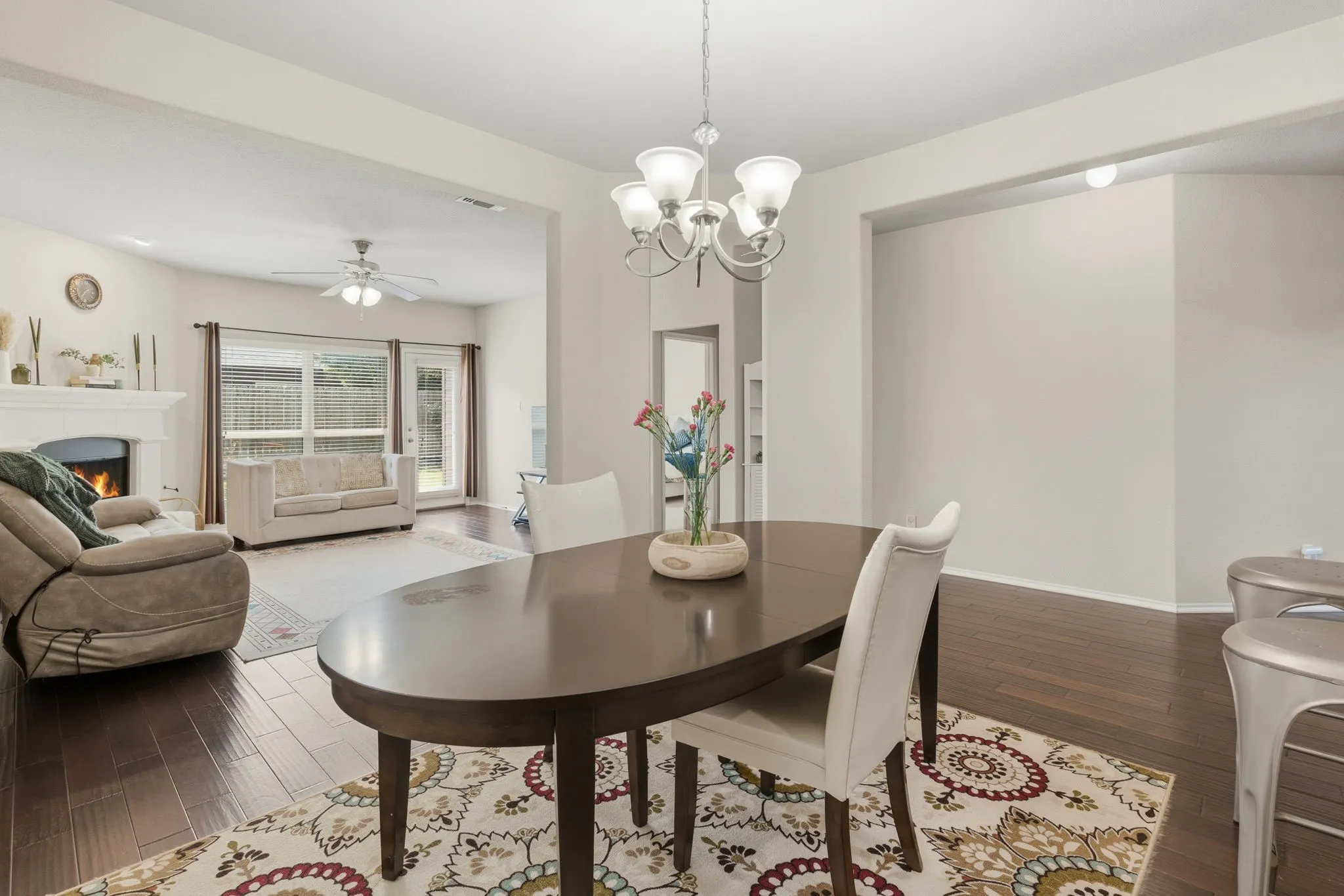 Hardwood-finish flooring, recessed lighting, and a chandelier illuminate the open-concept living space