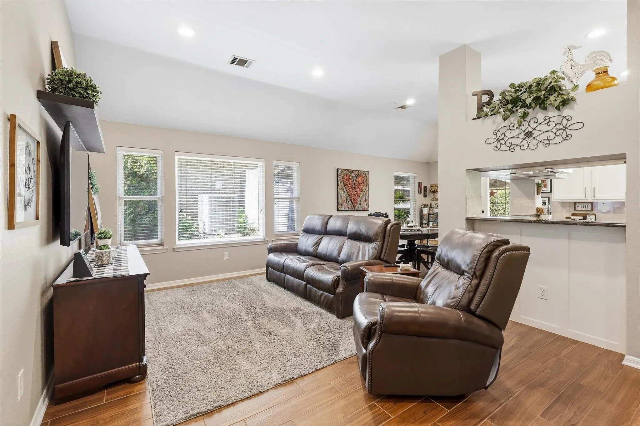 Vaulted ceiling, recessed lighting, wood-finish flooring, multiple windows, and a built-in pass-through counter