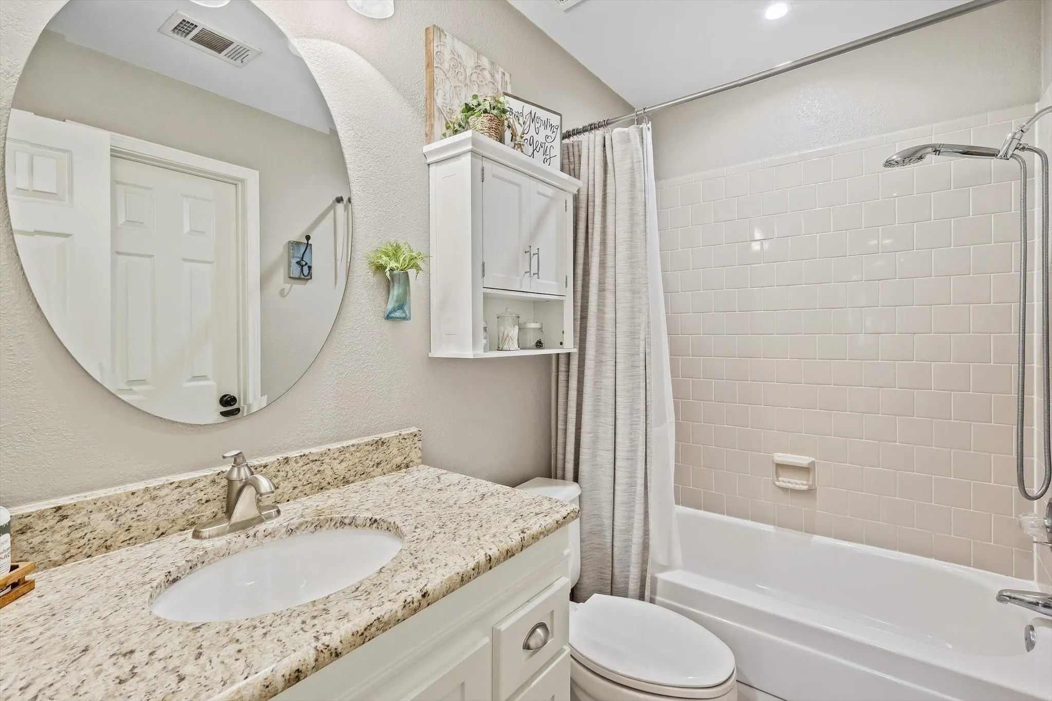 Bathroom featuring a white vanity with a granite-style countertop, undermount sink, and brushed nickel faucet