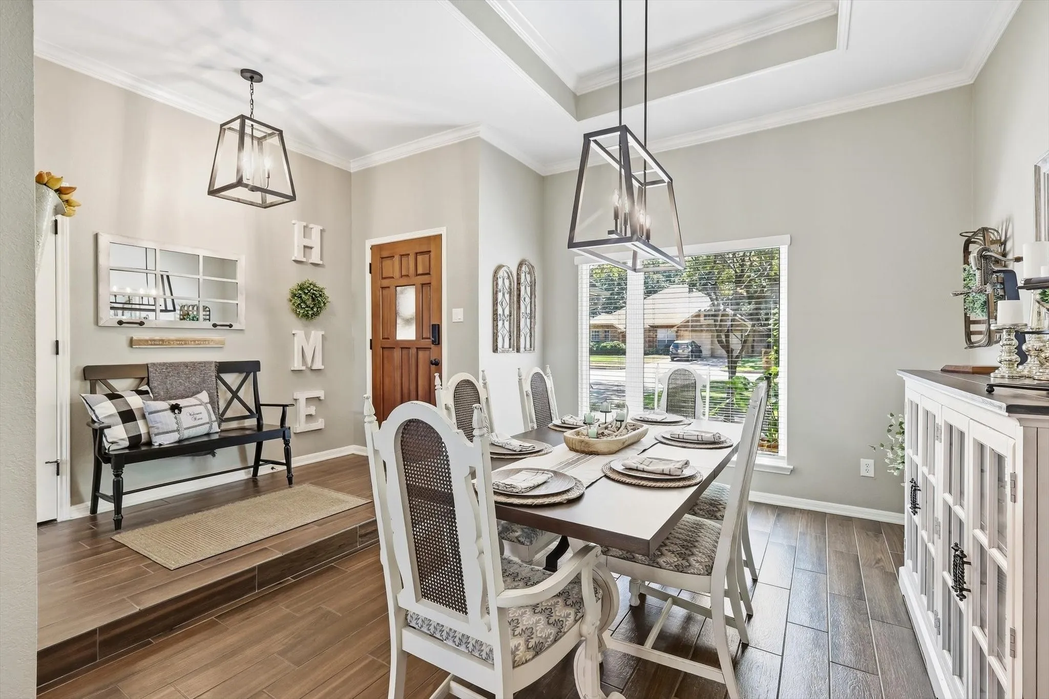 Wood-finish flooring throughout, tray ceiling with crown molding, and two contemporary pendant lights