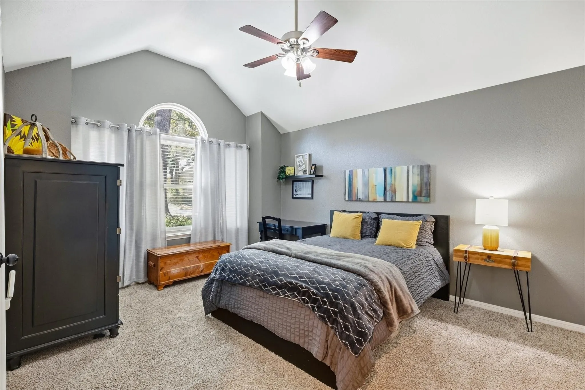 Vaulted ceiling with ceiling fan, arched window, and carpeted flooring