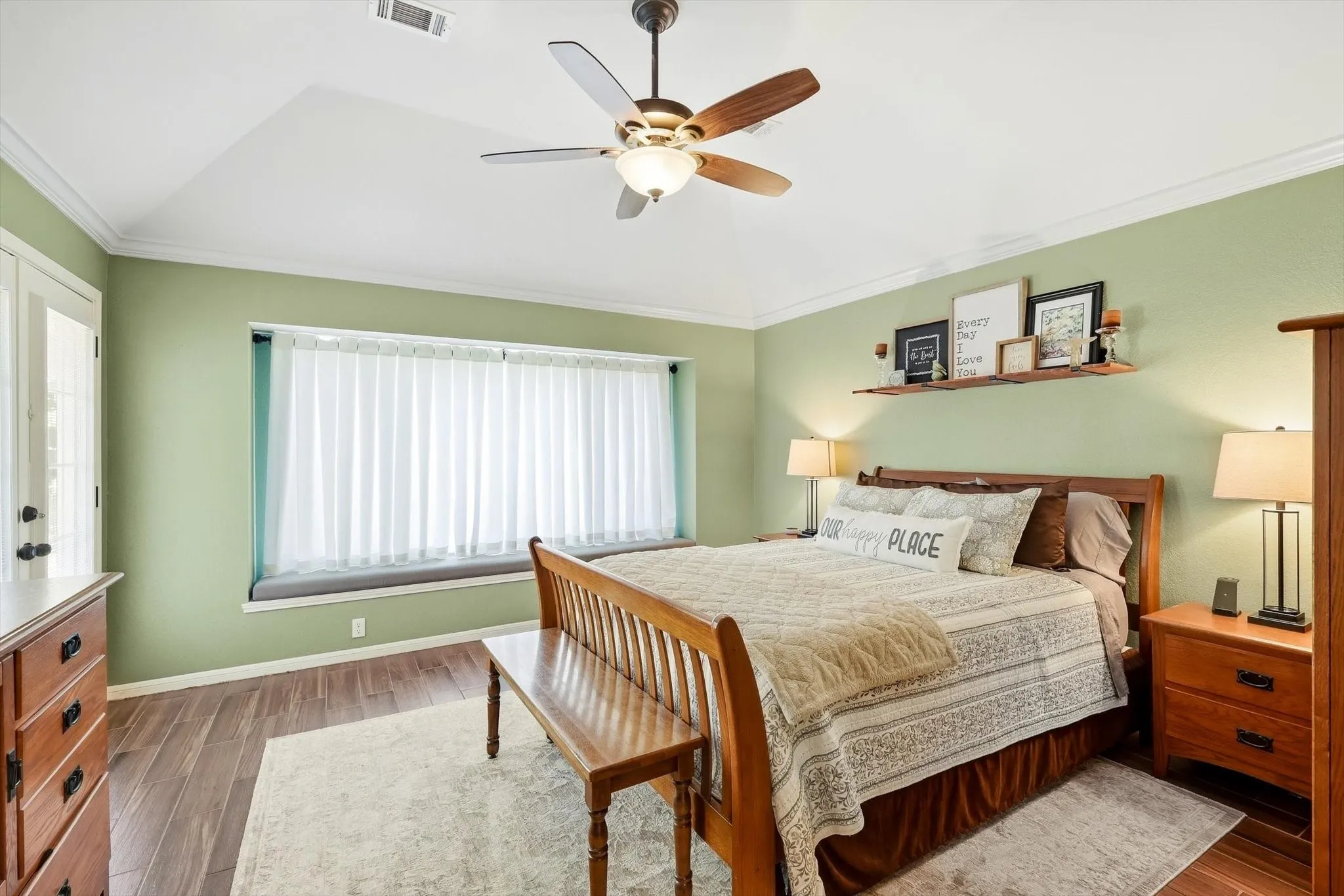 Tray ceiling with a ceiling fan, wood-finish flooring, built-in window seating, and a wall-mounted shelf