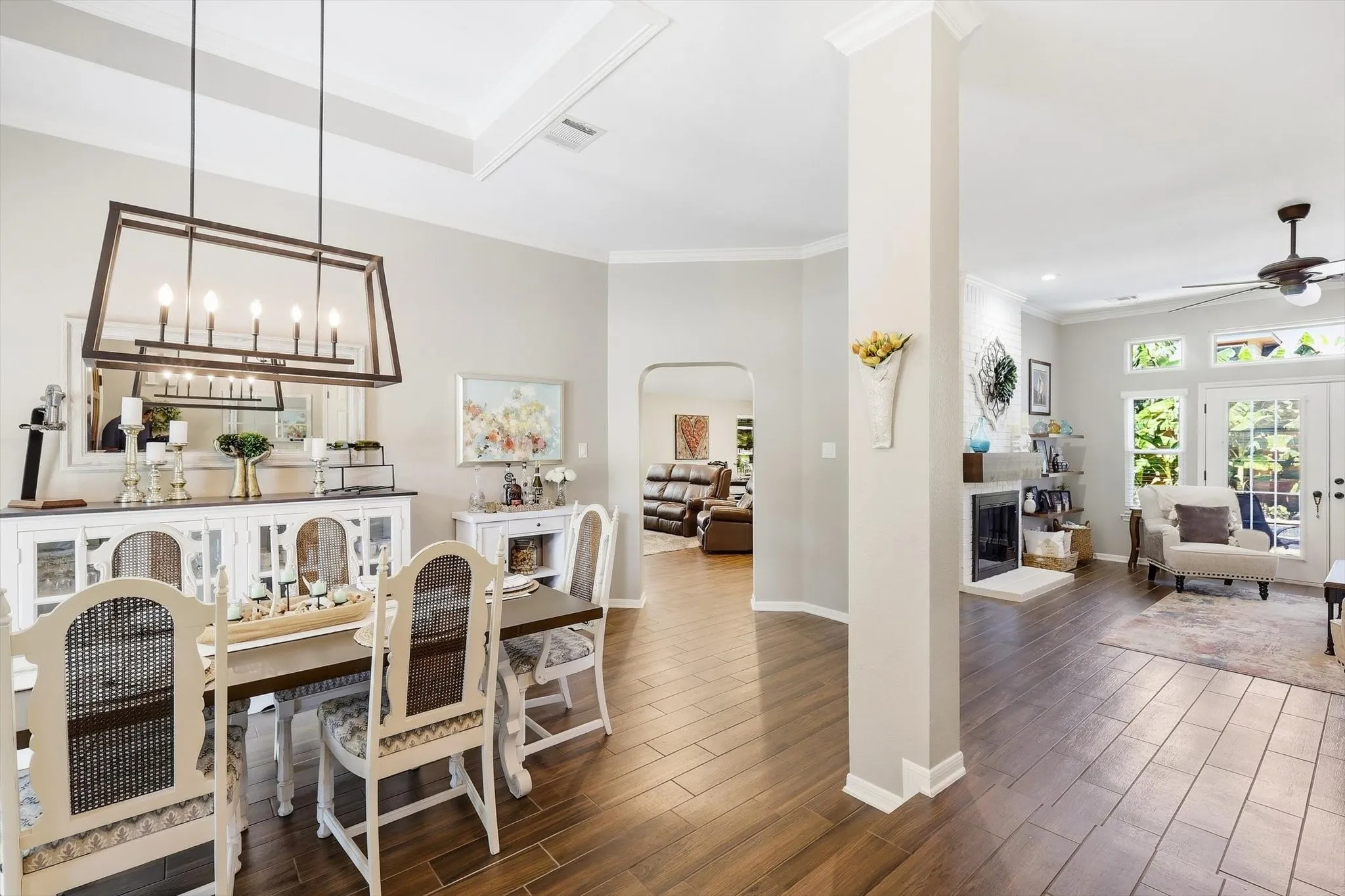 Recessed tray ceiling with crown molding, wood-finish flooring, built-in fireplace, and French doors