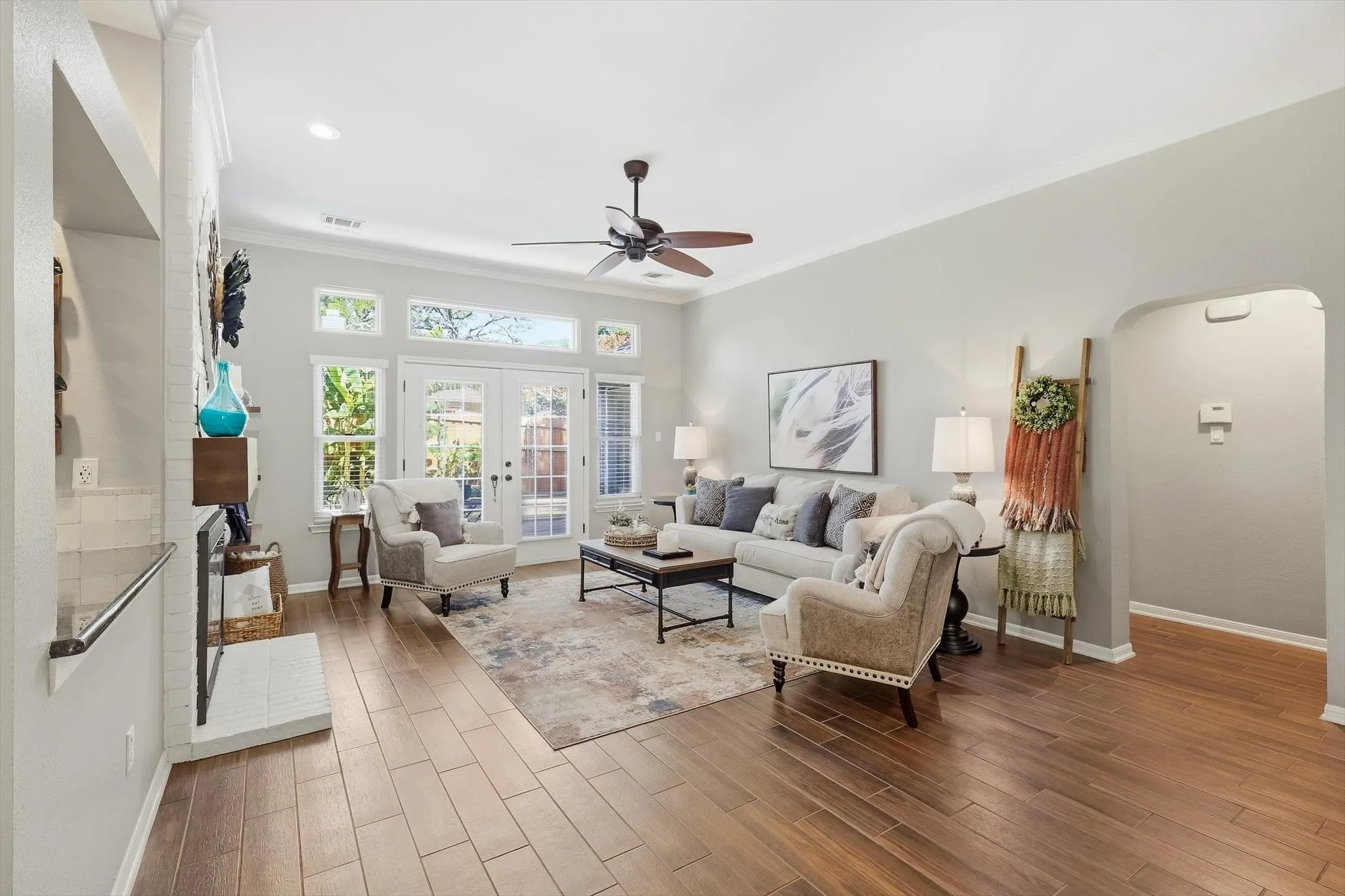 Spacious living area featuring wood-finish flooring, a ceiling fan, and crown molding