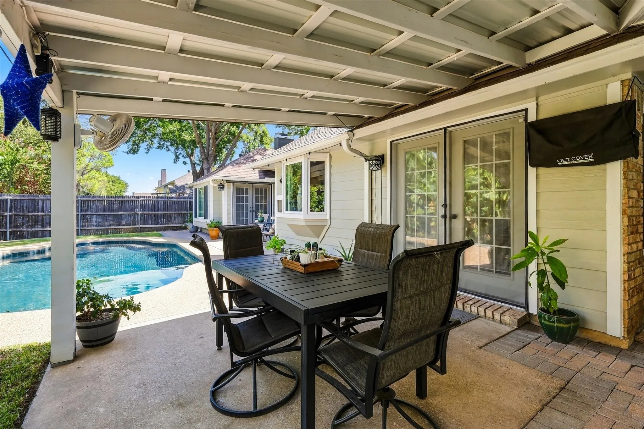 Covered patio with a ceiling fan, concrete flooring, and French doors leading to the interior