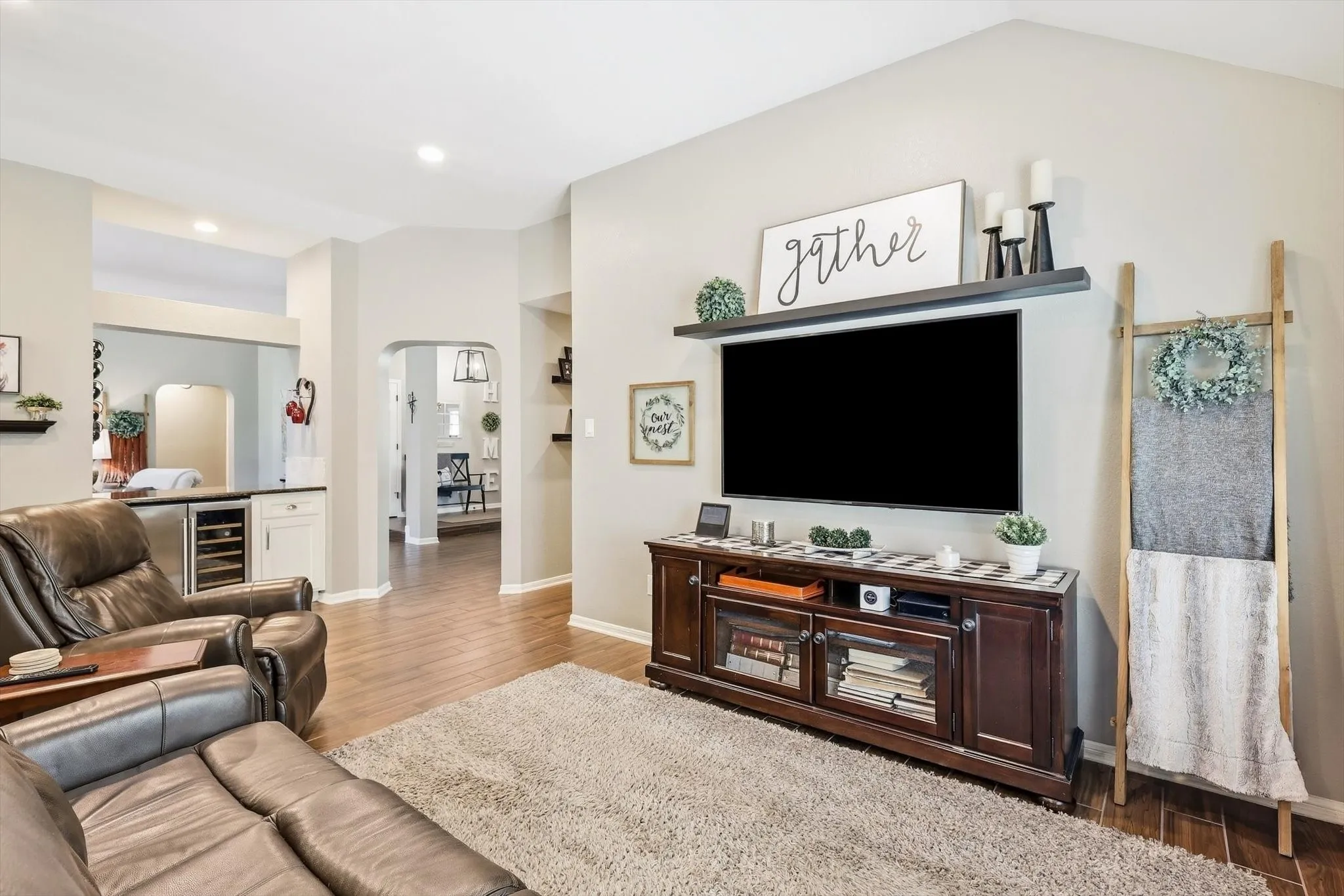 Vaulted ceiling, recessed lighting, wood-finish flooring, built-in shelving, and a wet bar with a wine refrigerator