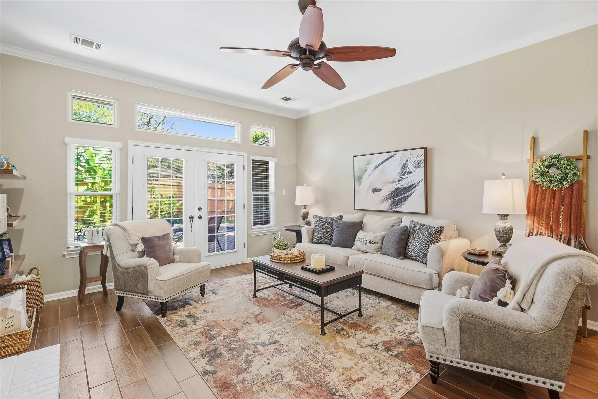 High ceilings with a ceiling fan, wood-finish flooring, and multiple windows including transoms, and French doors