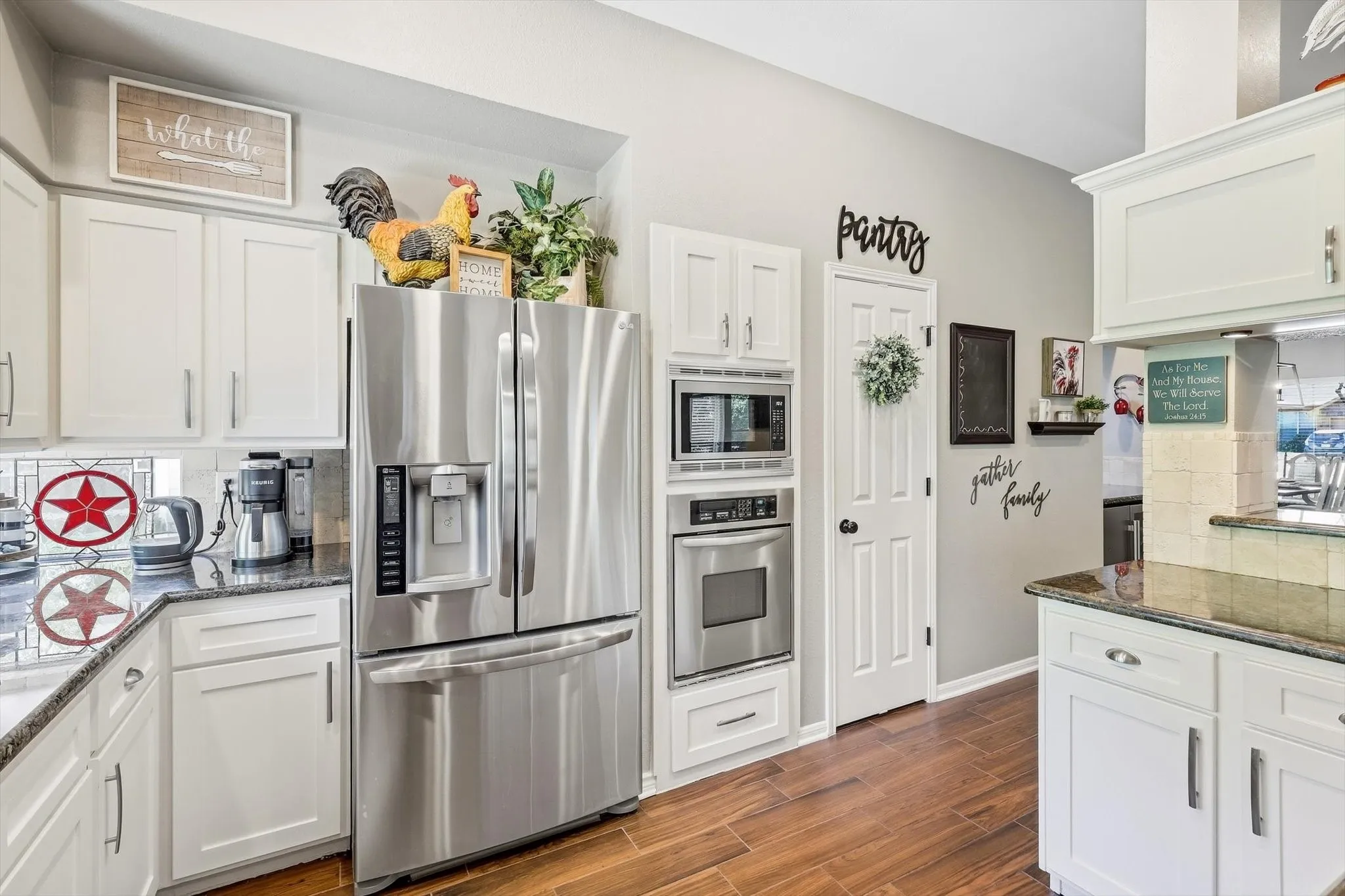 White cabinetry with sleek hardware, granite countertops, wood-finish flooring, stainless steel French door refrigerator, and built-in stainless steel microwave and oven
