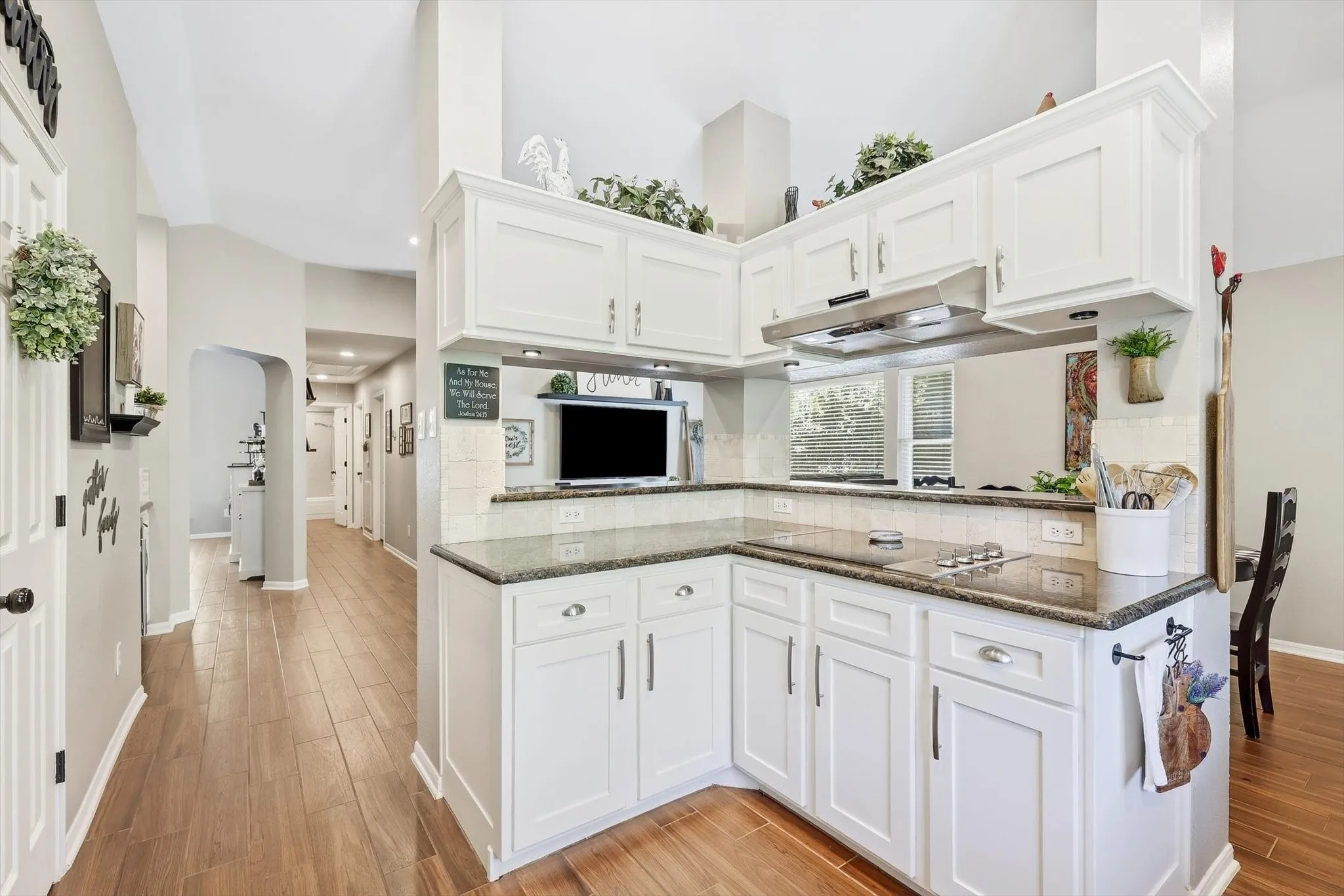 Kitchen featuring white cabinetry, granite countertops, tile backsplash, and wood-finish flooring