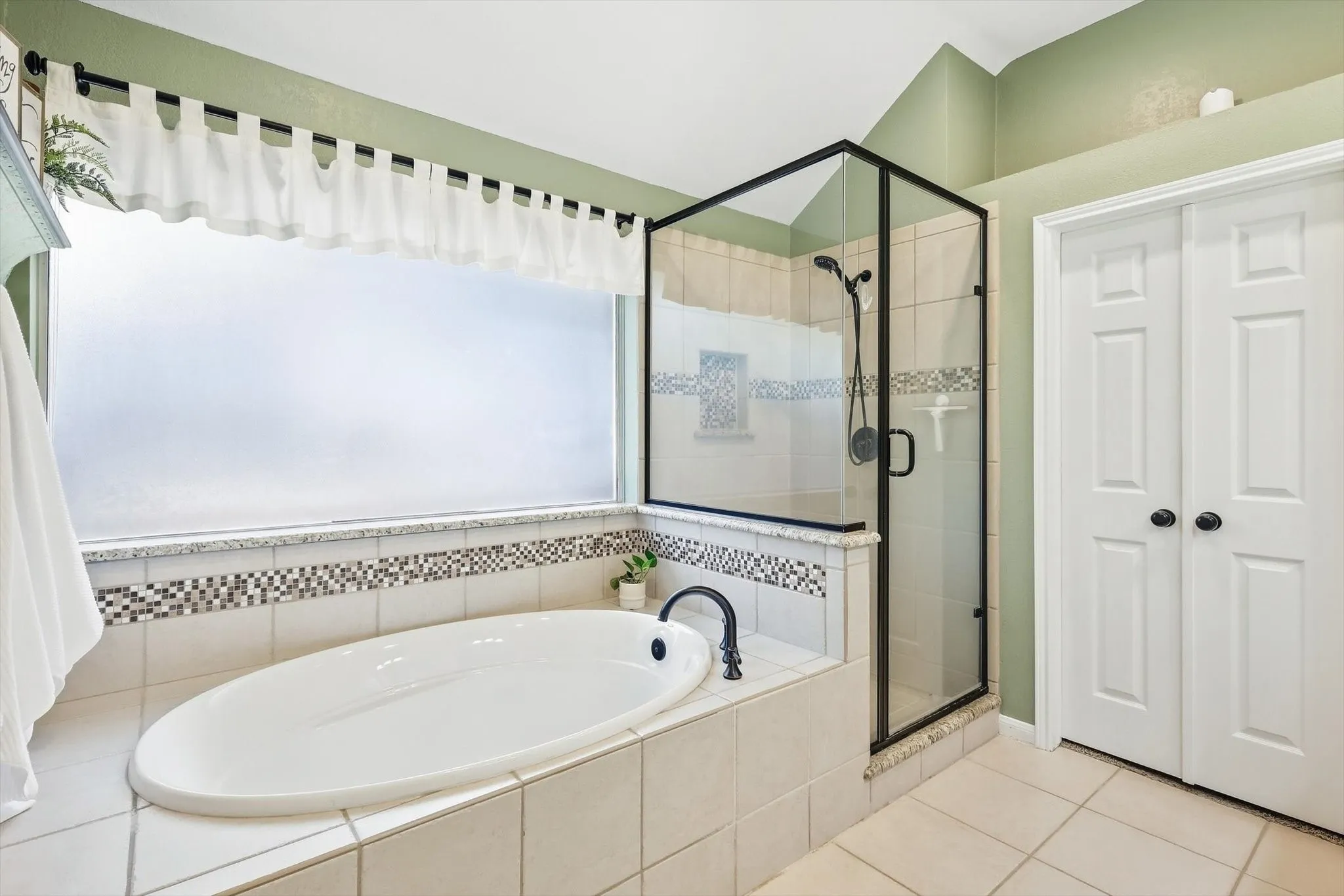 Soaking tub with black-finish faucet, tile surround, and mosaic tile accent
