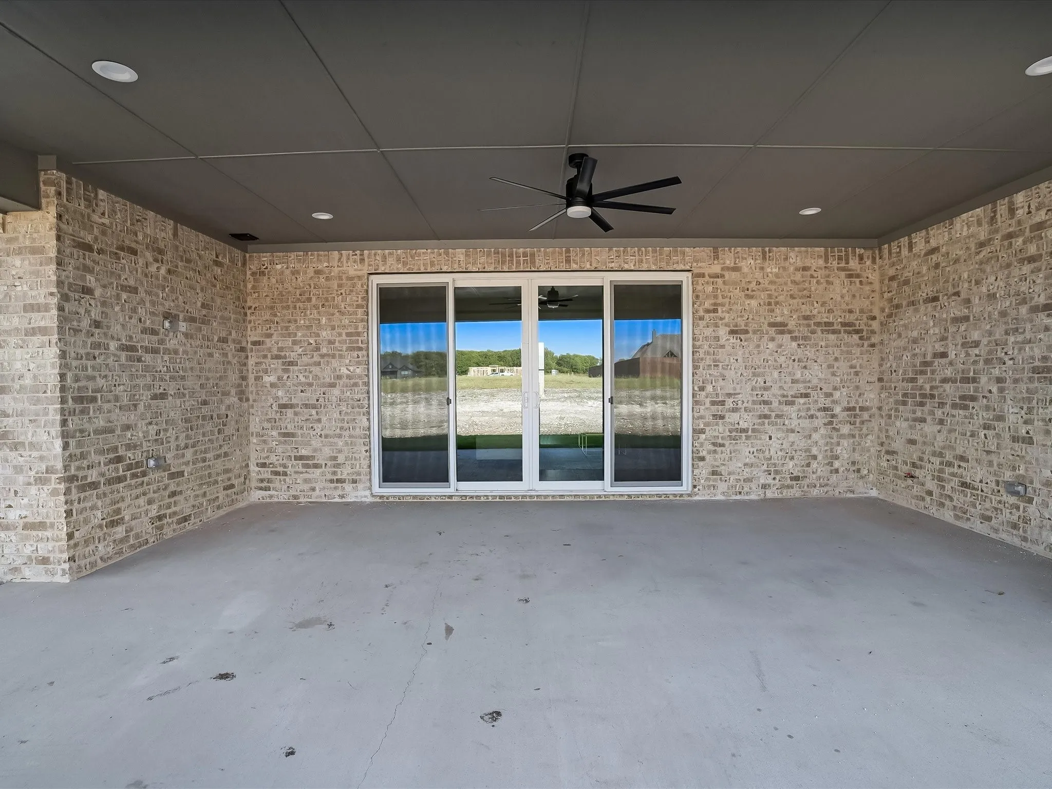 Covered patio featuring a ceiling fan, recessed lighting, brick walls, and a multi-panel sliding glass door