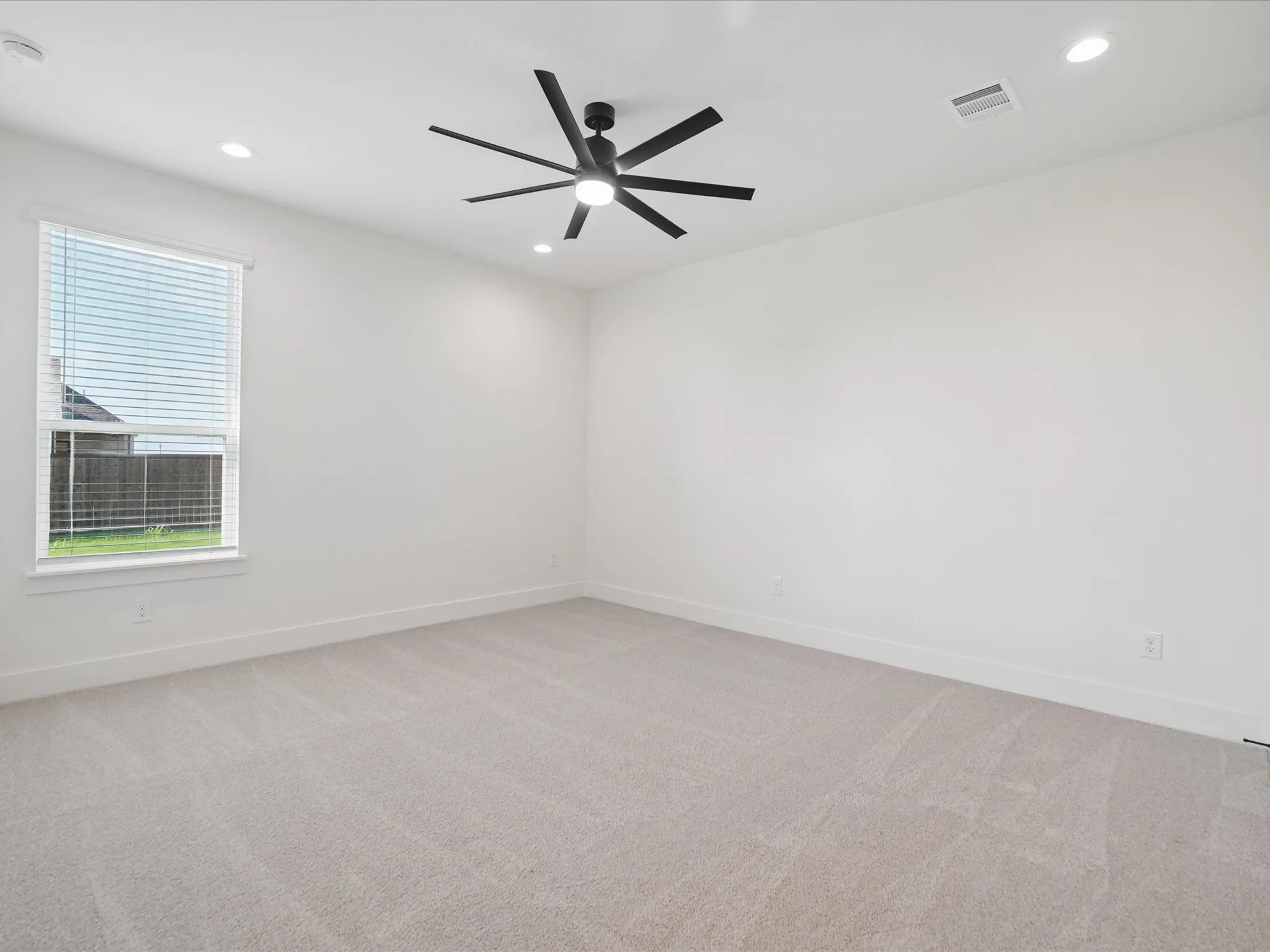 Recessed lighting, ceiling fan with black blades, white window blinds, and light-colored carpeting