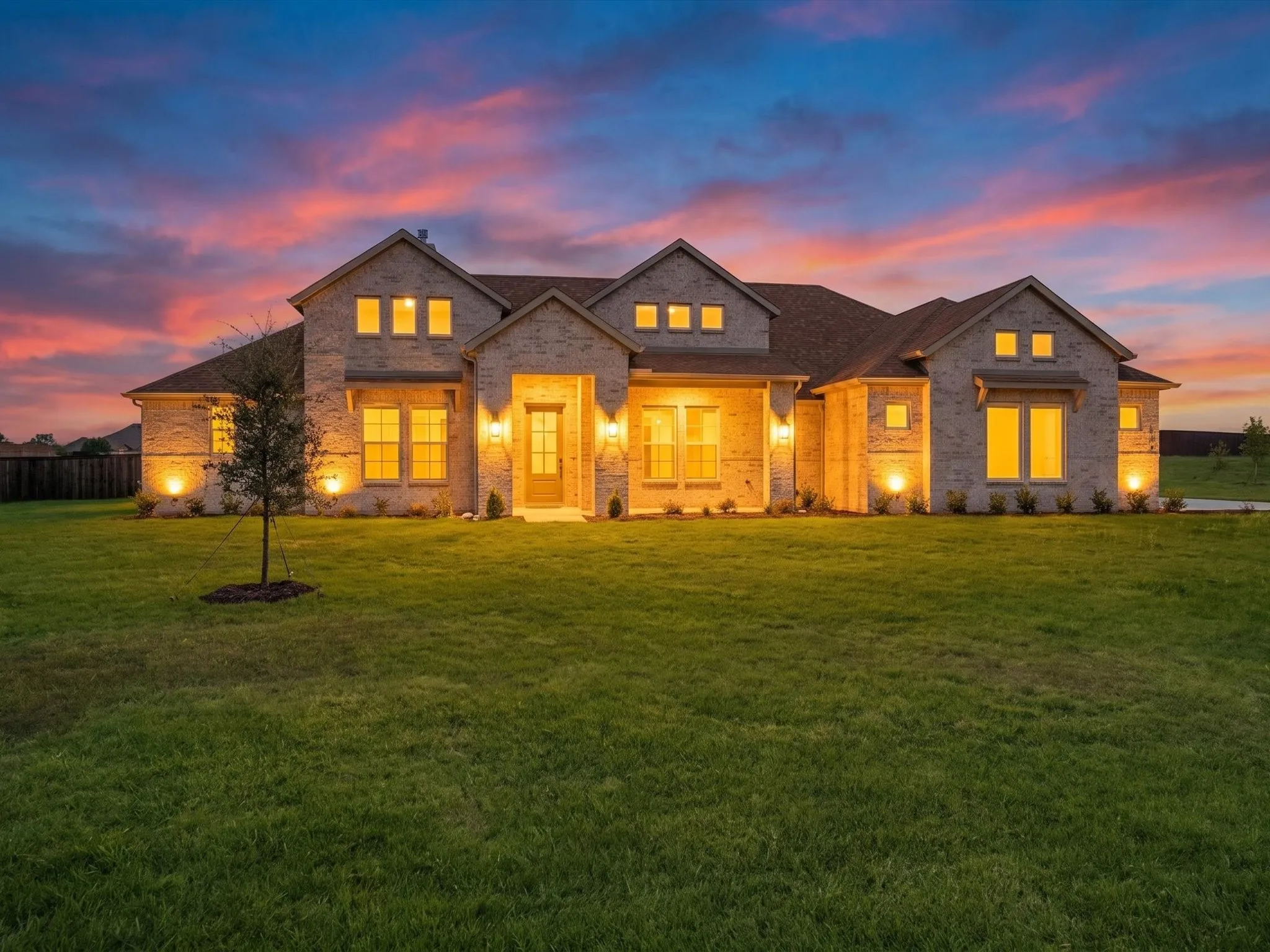 Brick exterior featuring multiple gables, extensive landscaping, and outdoor lighting