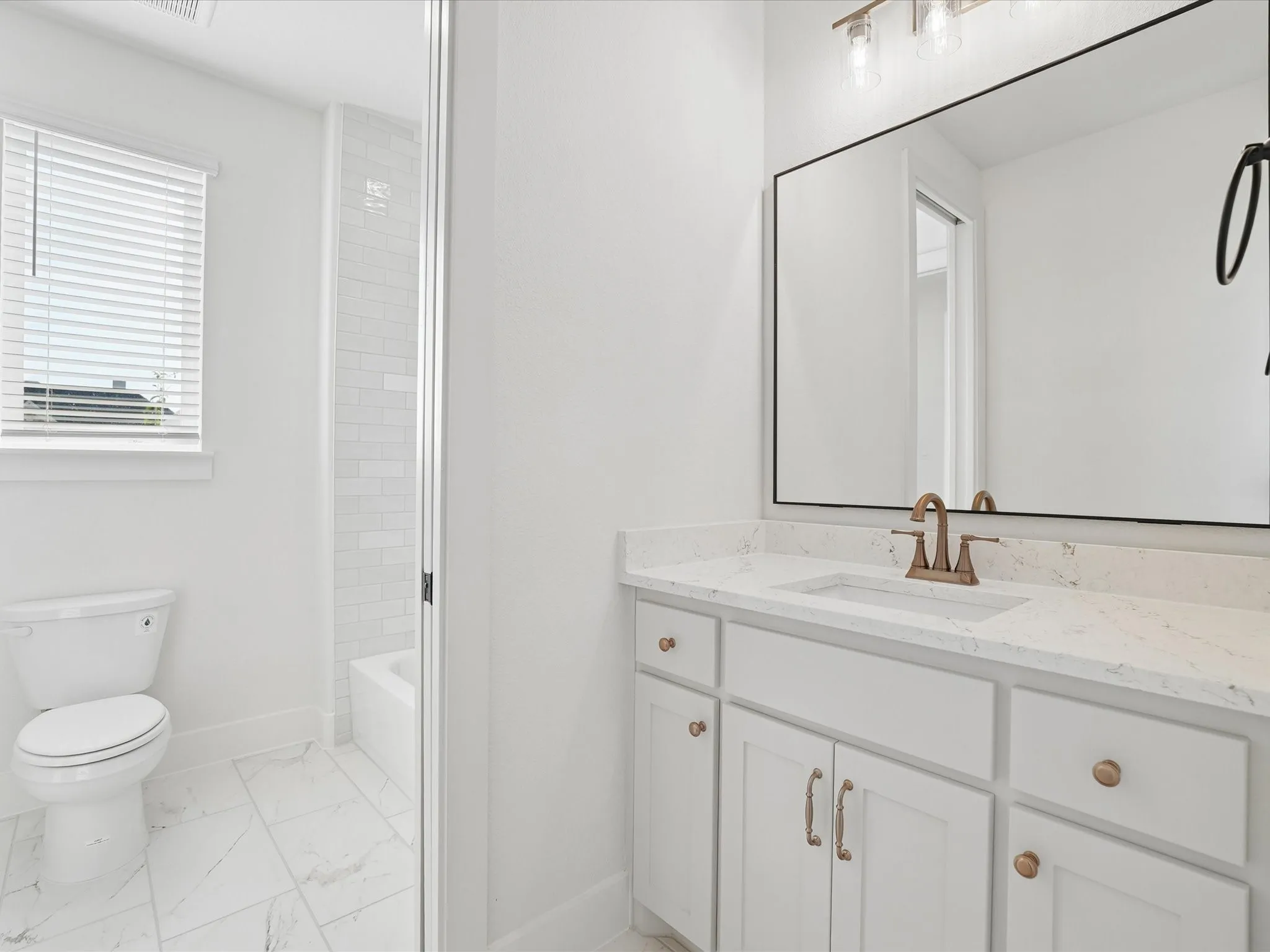White vanity with a quartz countertop, bronze-finish faucet, and rectangular undermount sink