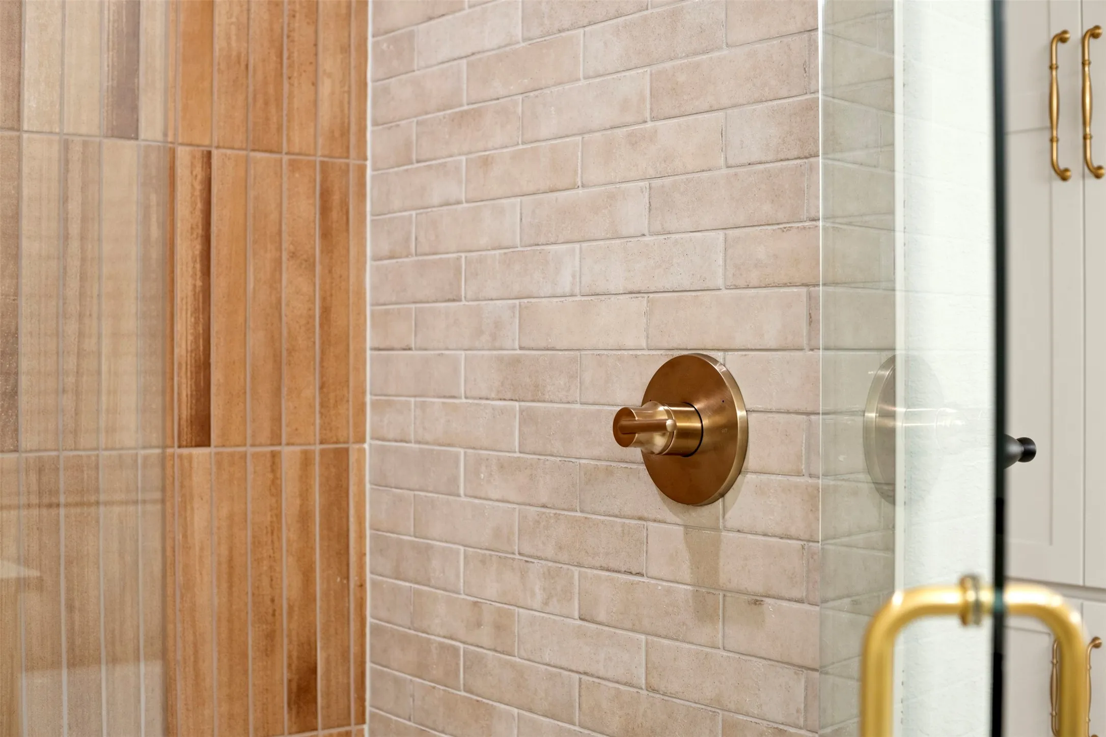 Spa-inspired bathroom featuring subway tile walls in warm neutral tones, brushed bronze shower valve with integrated trim, and glass shower enclosure