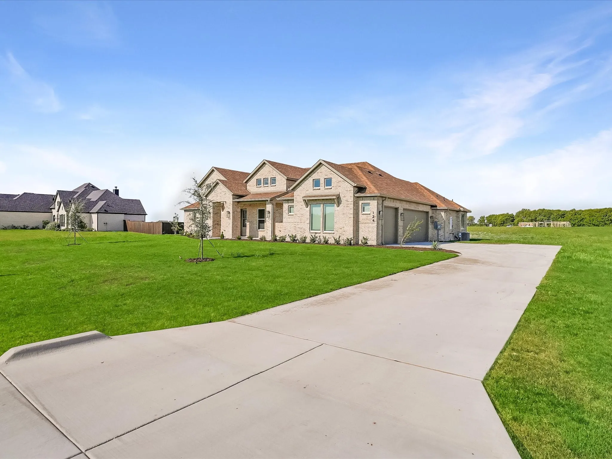 Stone veneer exterior with a gabled roof, a concrete driveway, and an attached two-car garage