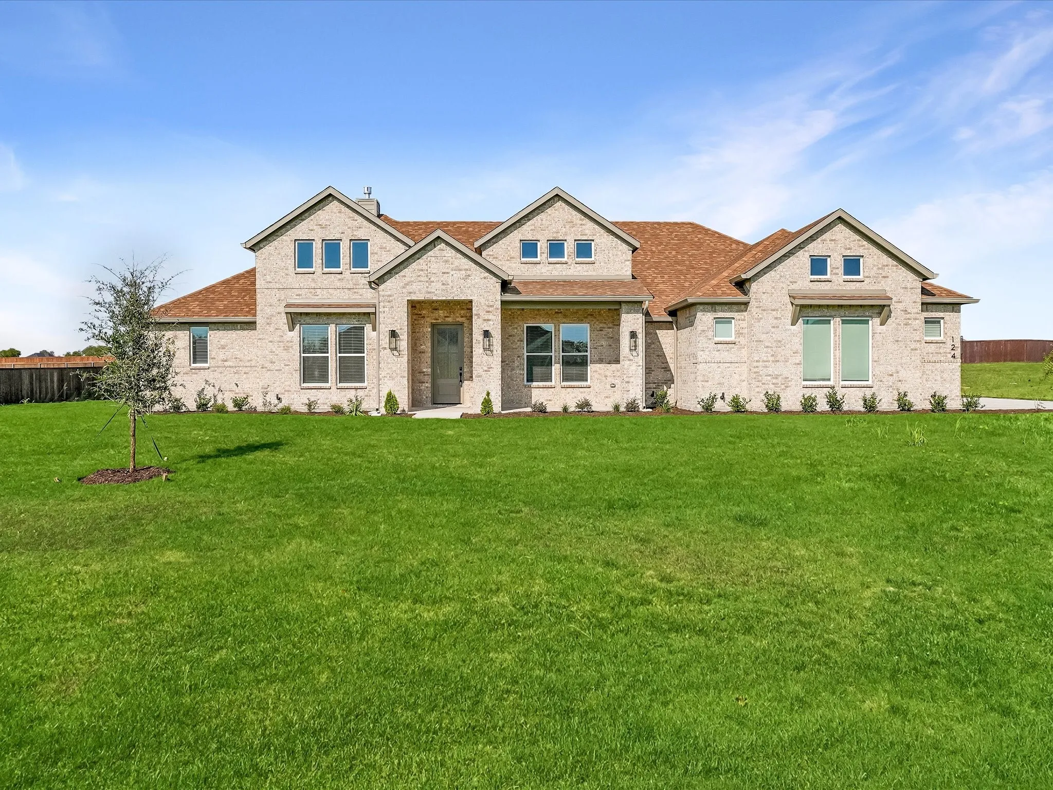 Brick exterior, gabled roofline, multiple windows, front landscaping, and a broad lawn