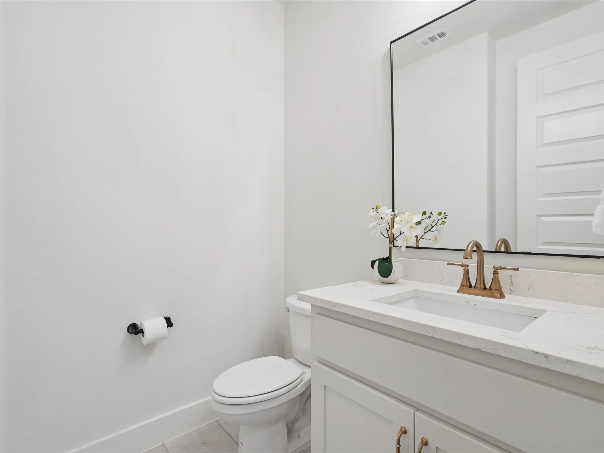 White vanity with an integrated sink, quartz countertop, and a black-framed mirror
