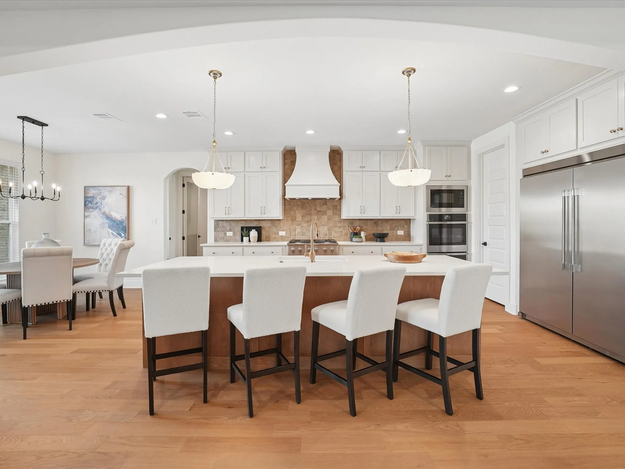 Gourmet kitchen with wood-finish flooring, a central island, stainless steel appliances, and white cabinetry