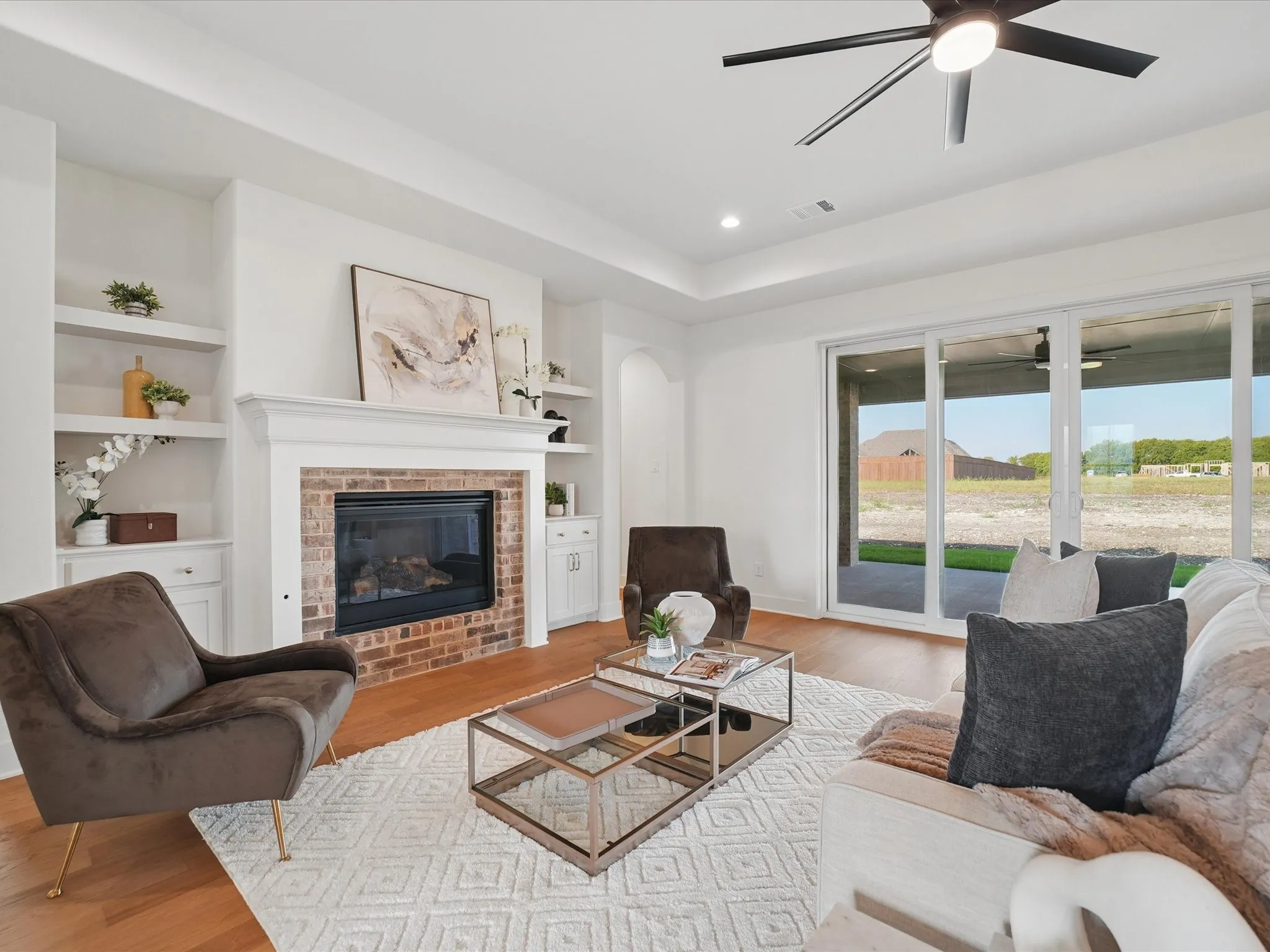 Brick-surround fireplace with white mantel, built-in shelving, wood-finish flooring, recessed lighting, and sliding glass doors