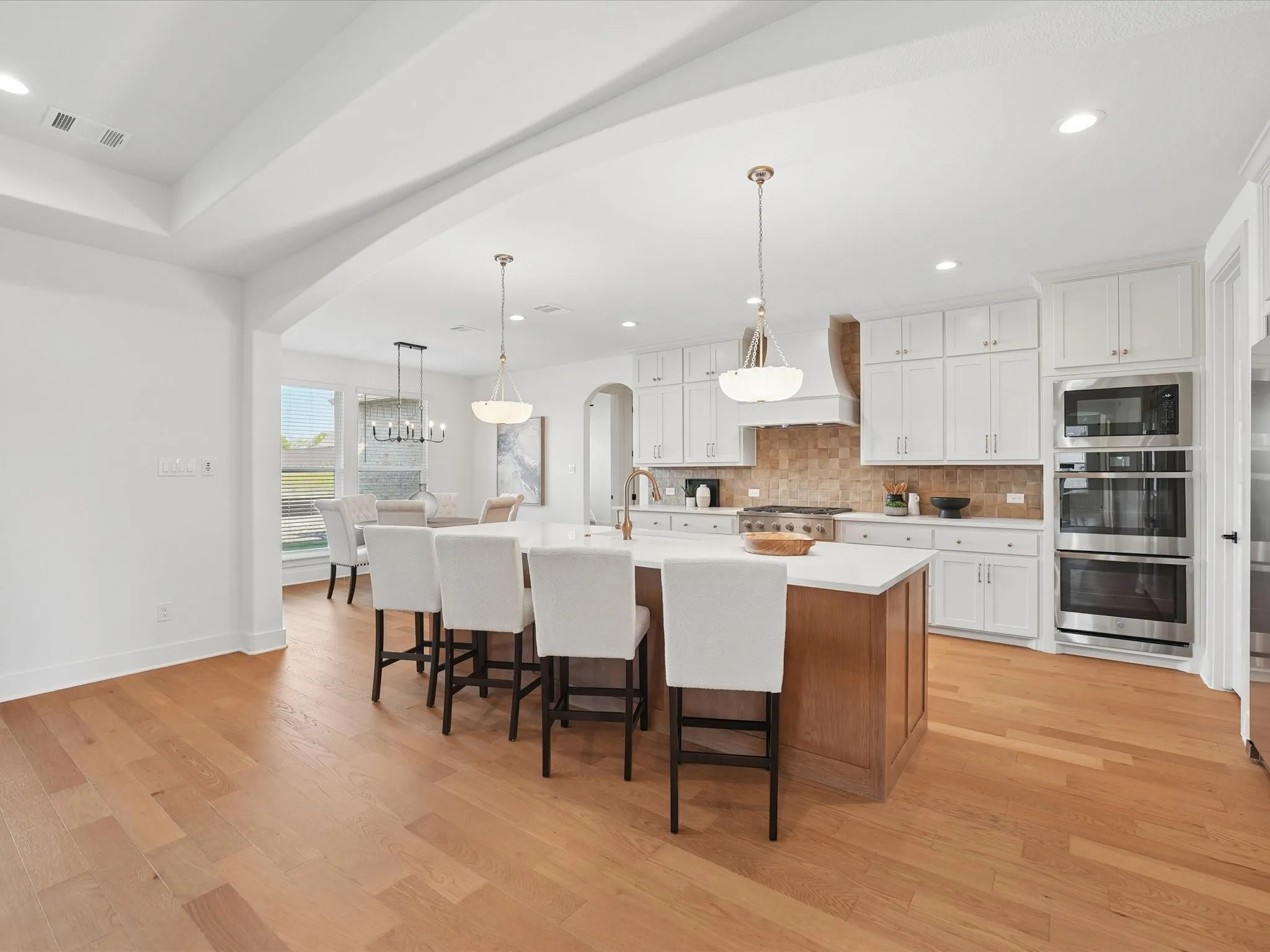 Gourmet kitchen with white cabinetry, stainless steel appliances, and a central island with countertop seating