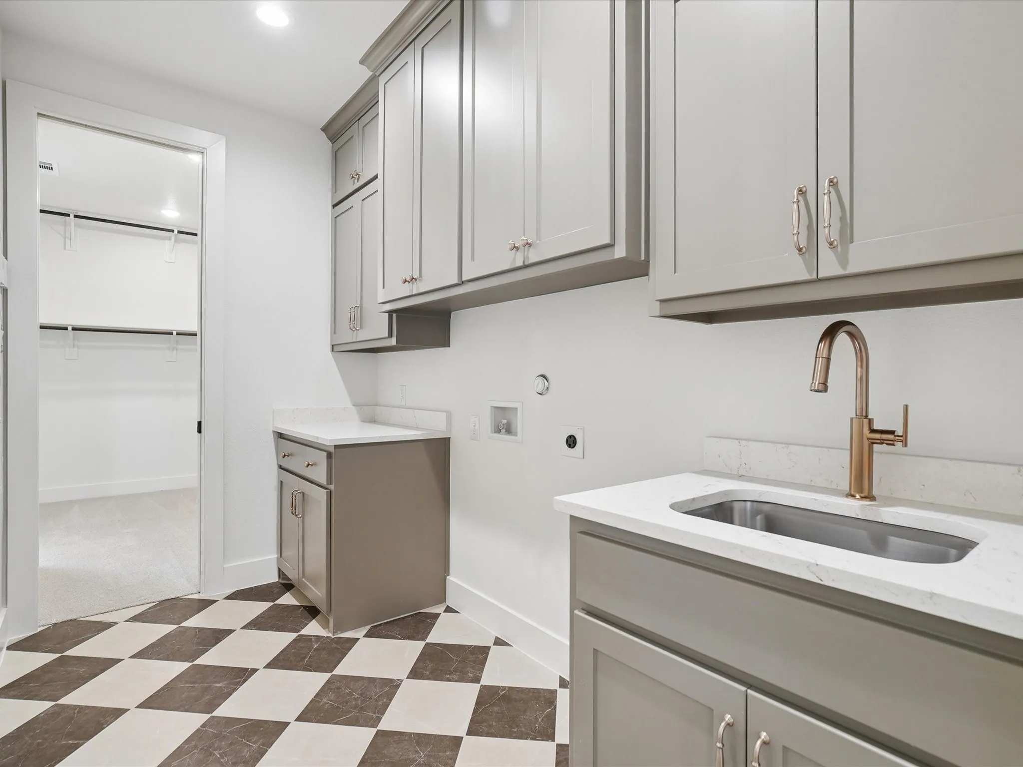 Chequered tile flooring, built-in cabinetry, quartz countertops, undermount sink, and a bronze-finish faucet