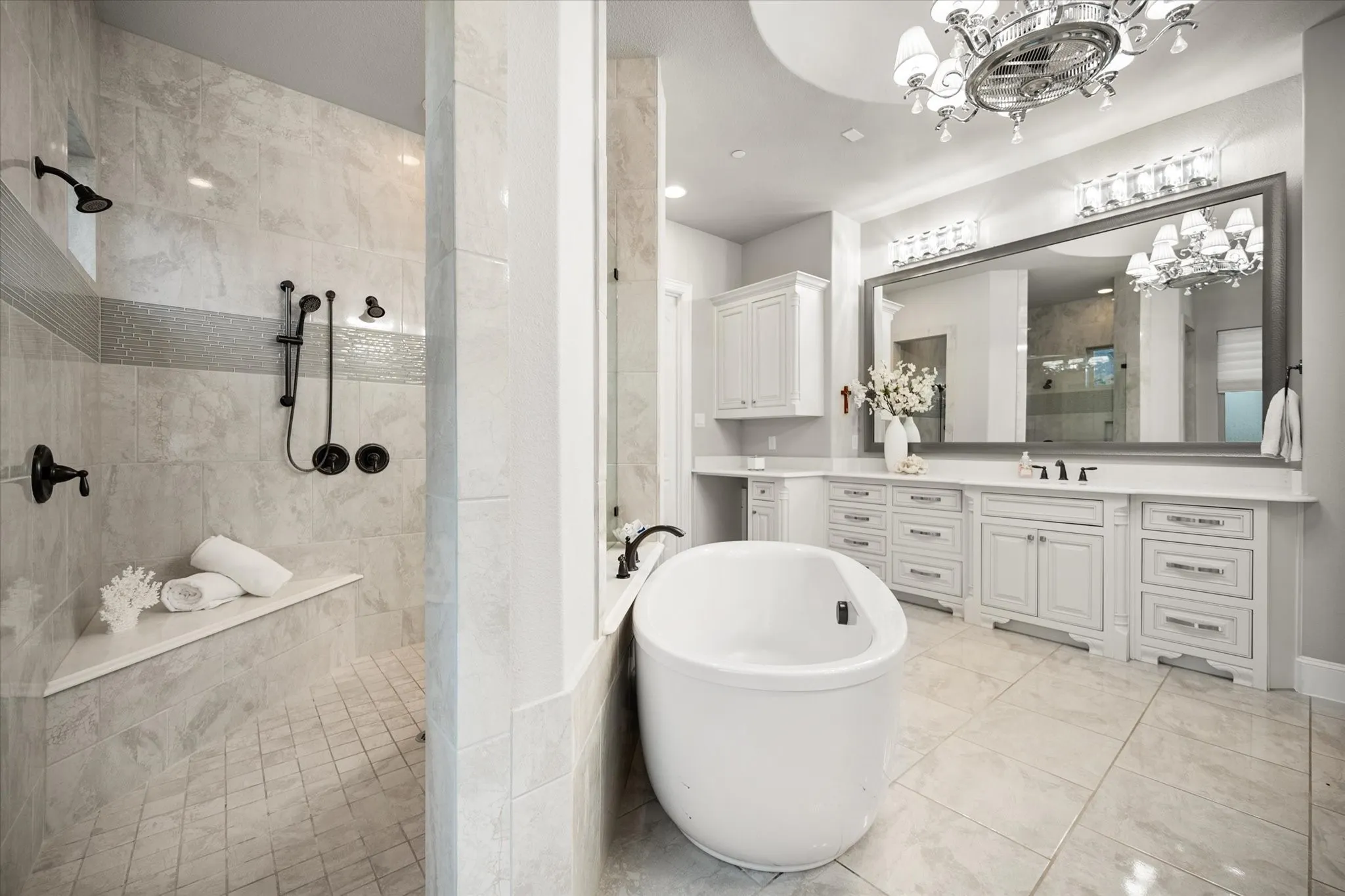 Spacious vanity with dual sinks, extensive cabinetry, and a large framed mirror
