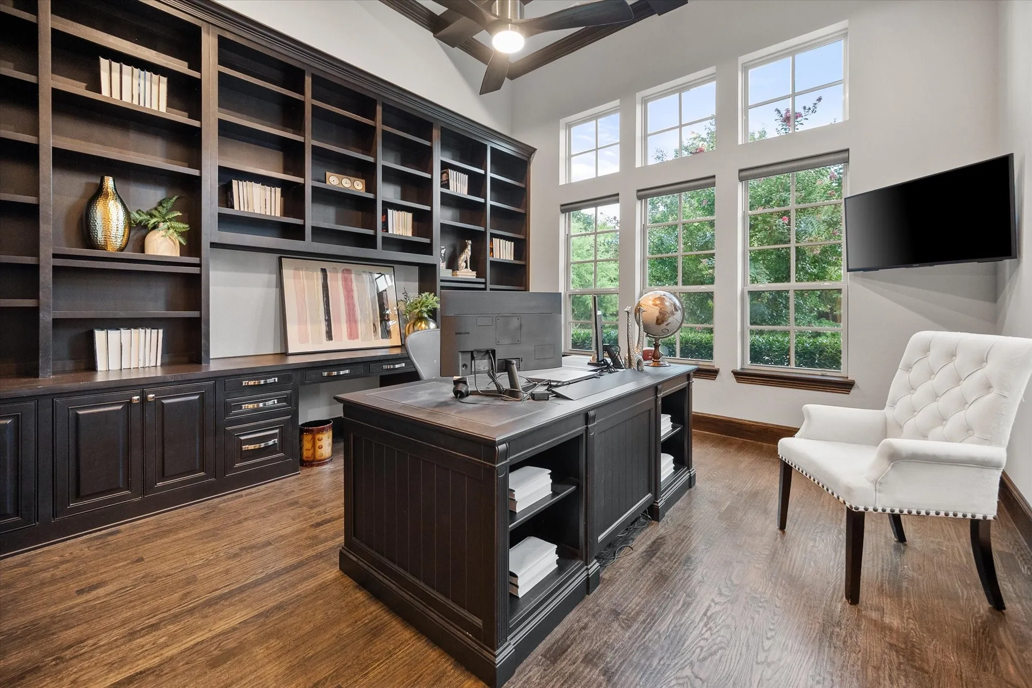Built-in dark wood cabinetry and shelving, wood-finish flooring, a ceiling fan, and transom windows