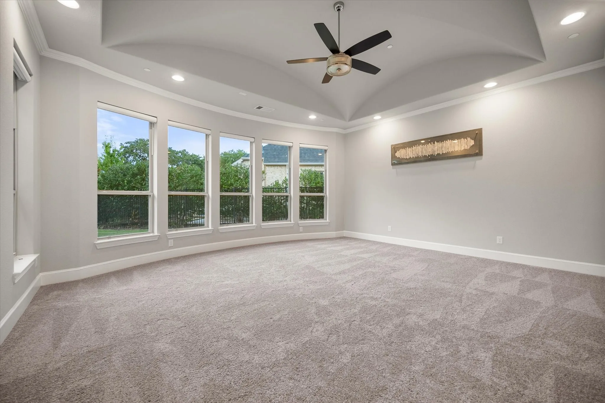 Coved ceiling with recessed lighting, ceiling fan, and five curved picture windows