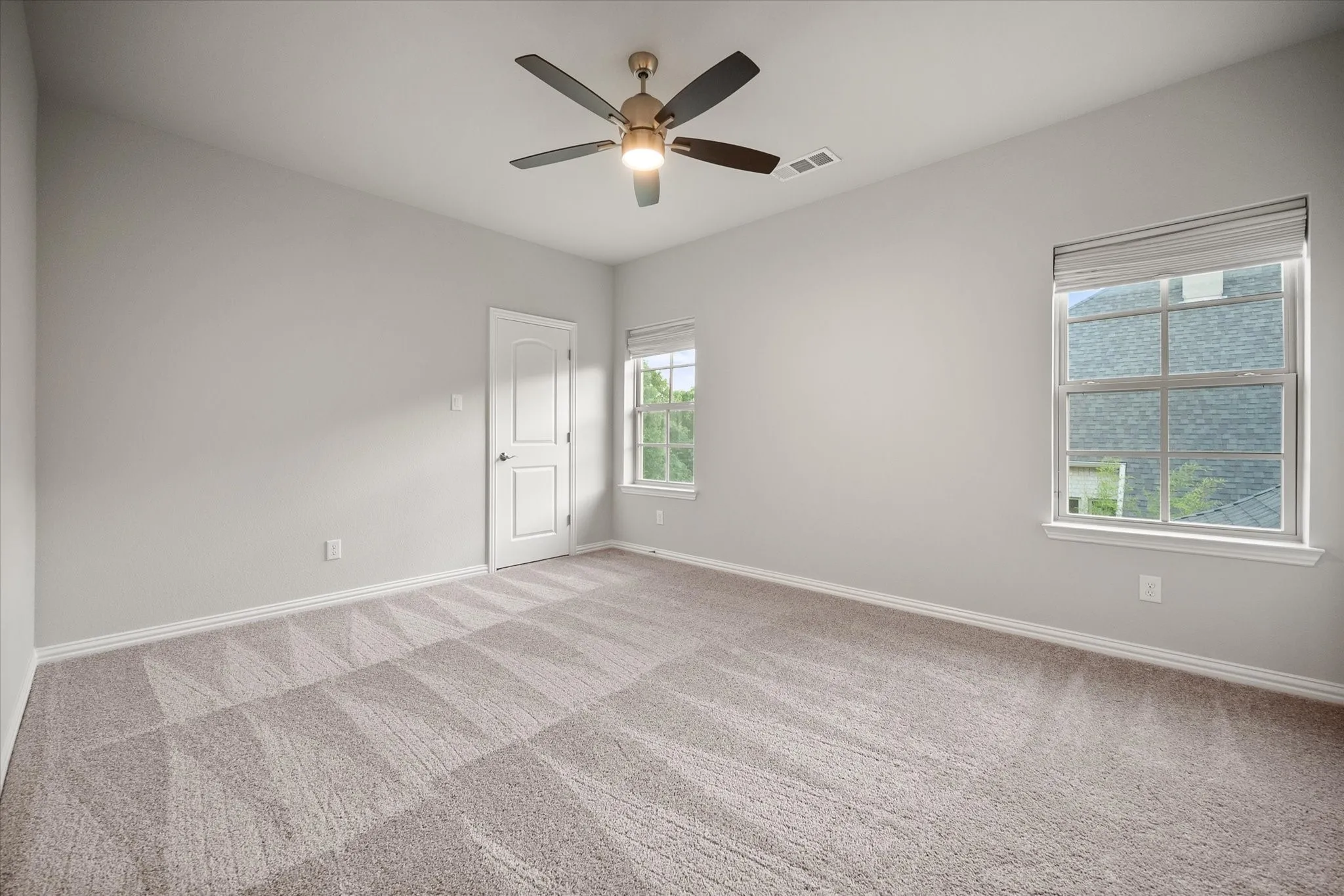 Neutral-toned carpeting, ceiling fan with integrated lighting, white trim, and two windows with blinds