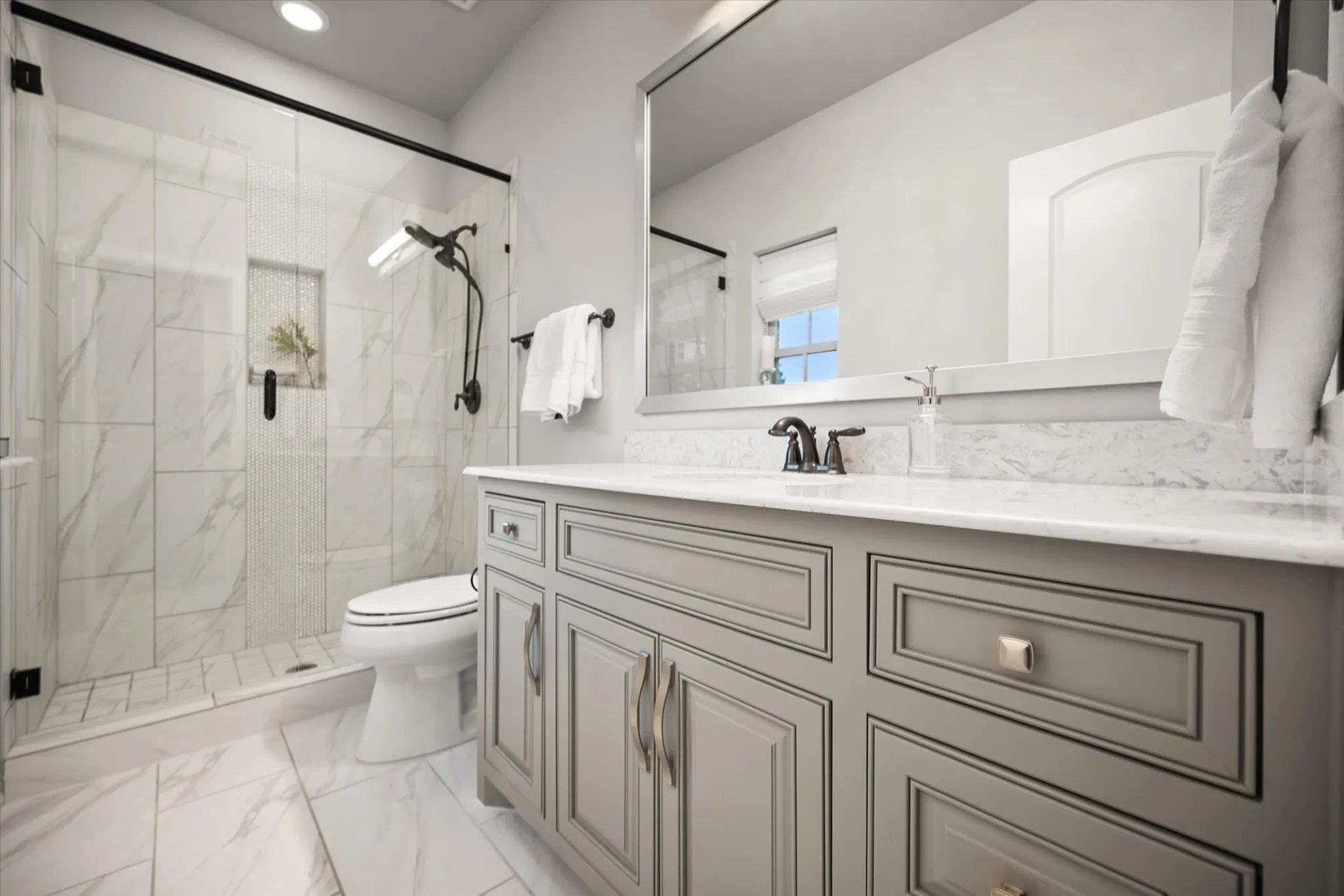 Walk-in shower with clear glass enclosure, a built-in shower niche, and black fixtures