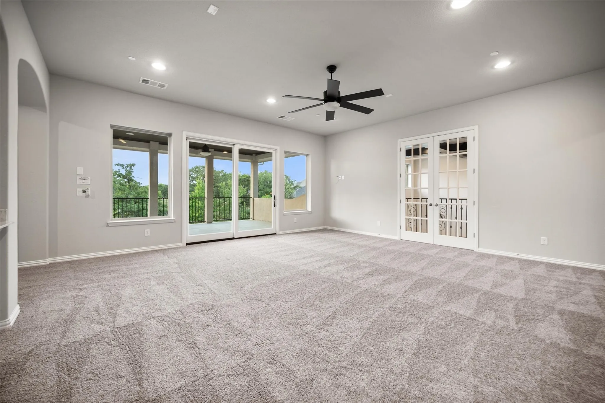 Spacious room with light gray carpet flooring, recessed lighting, and a ceiling fan