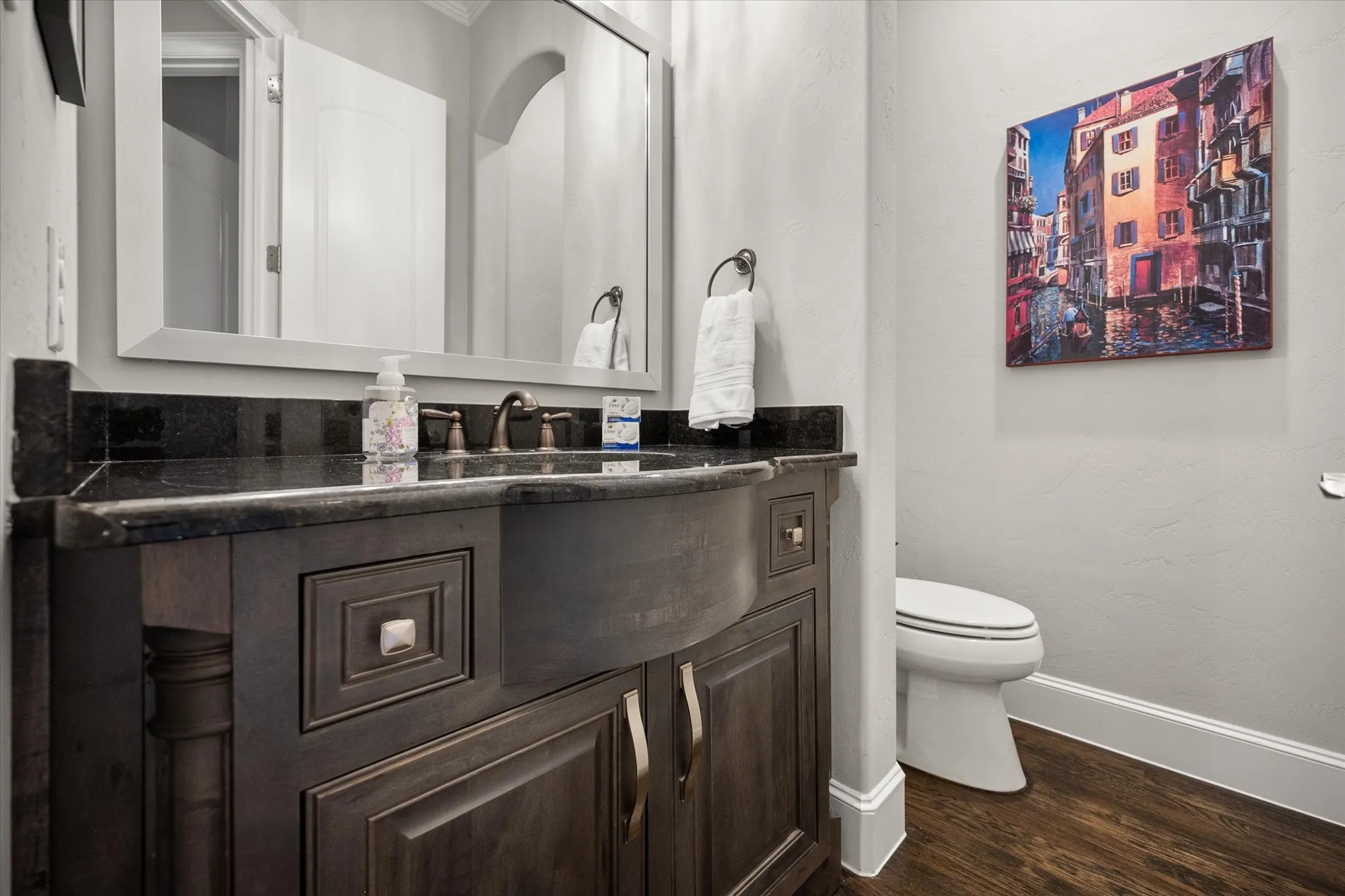 Dark wood-finish vanity with a dark countertop and undermount sink