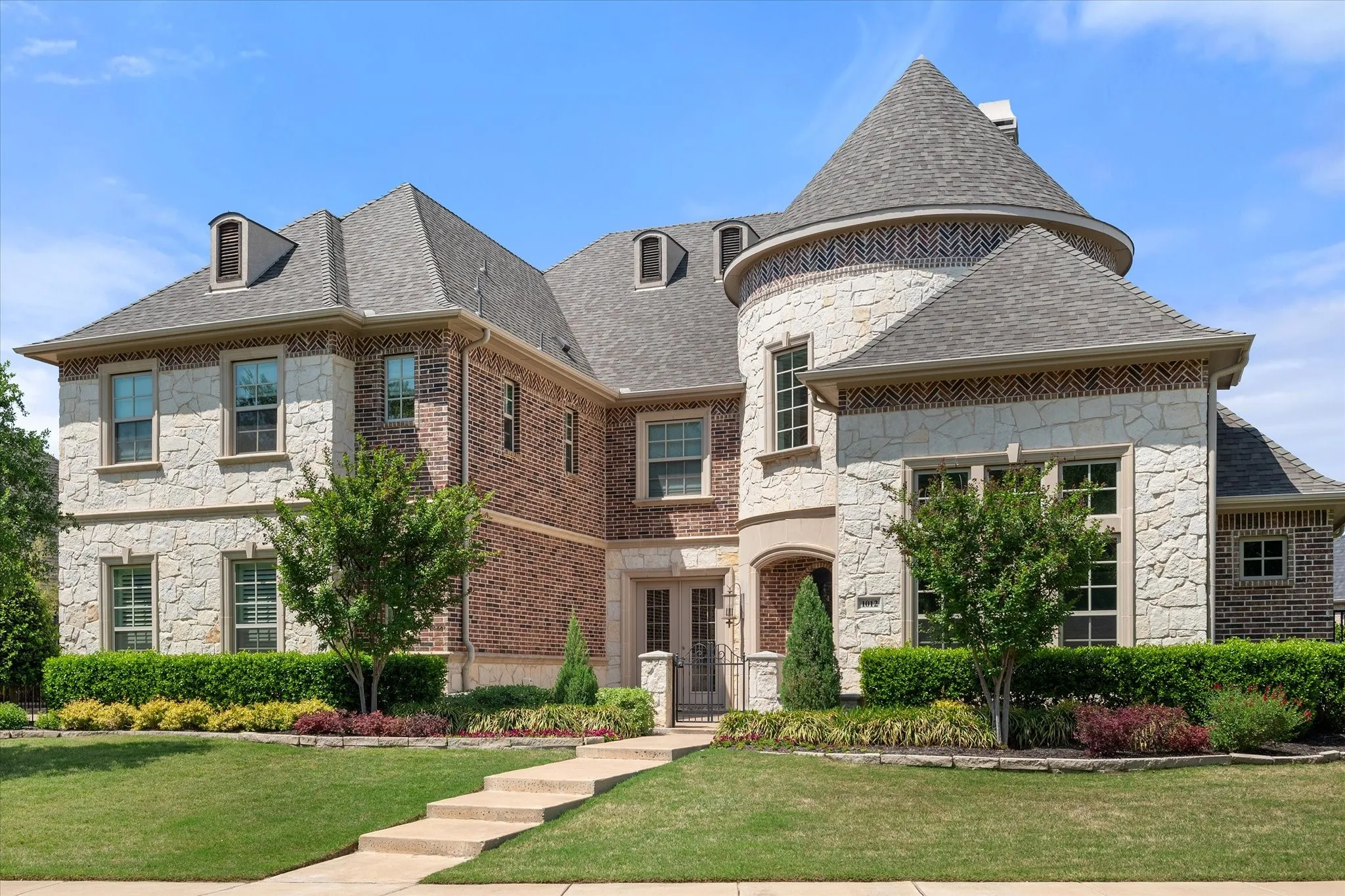 Stone and brick exterior with a turret, multiple dormer windows, and an arched entry