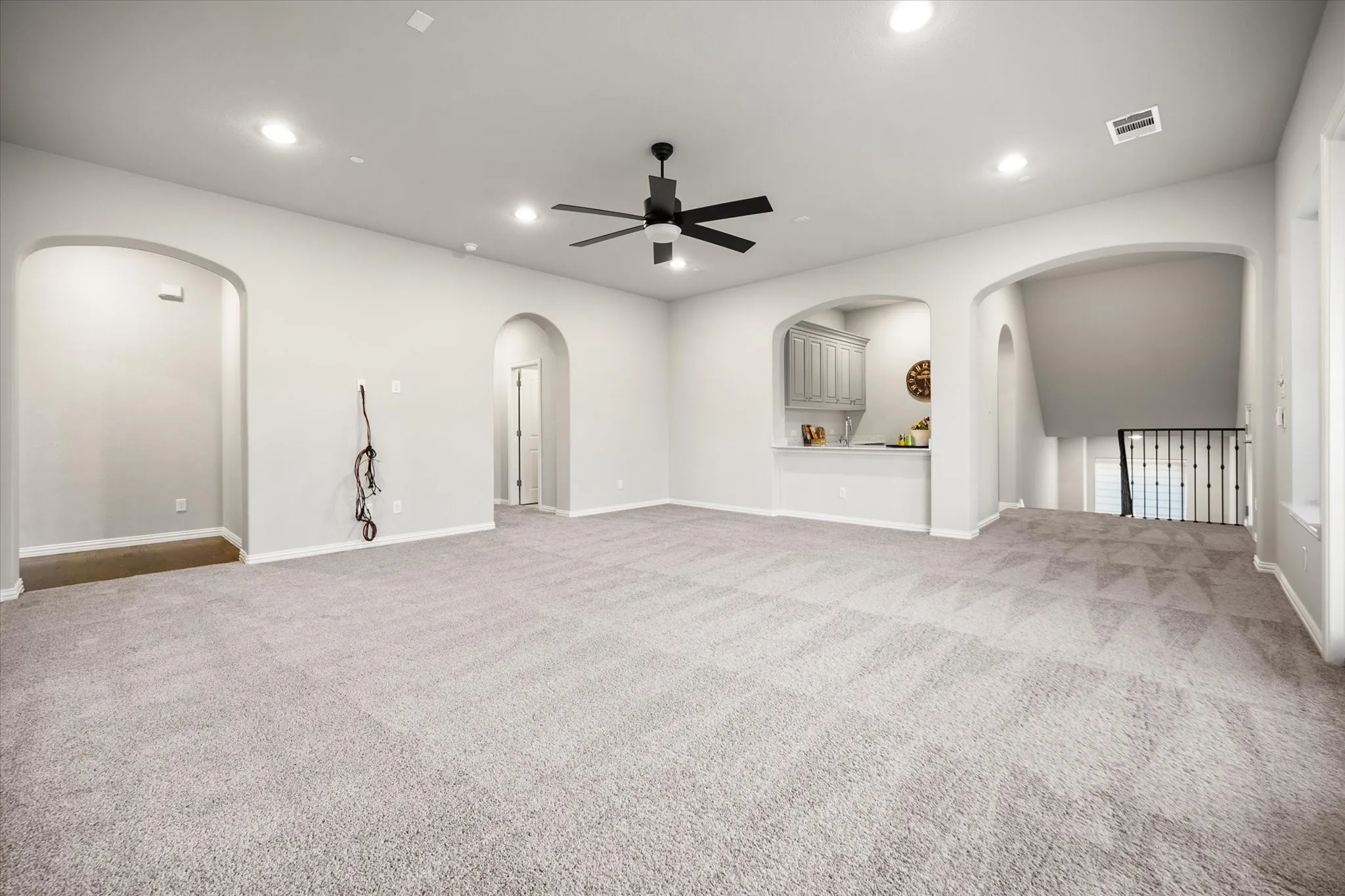 Recessed lighting, arched doorways, a ceiling fan, built-in cabinetry, and carpeted flooring