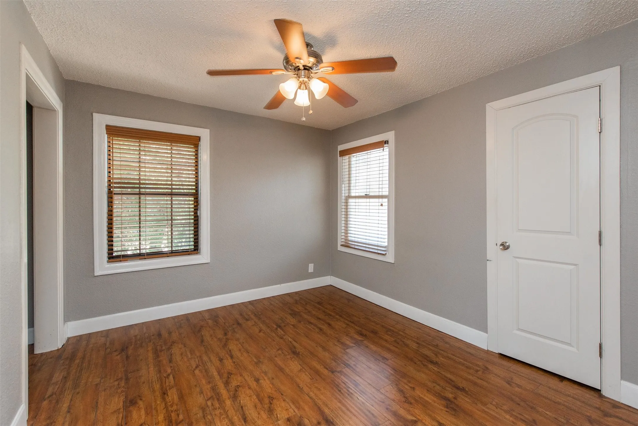 Unfurnished room with a textured ceiling, wood-type flooring, and ceiling fan
