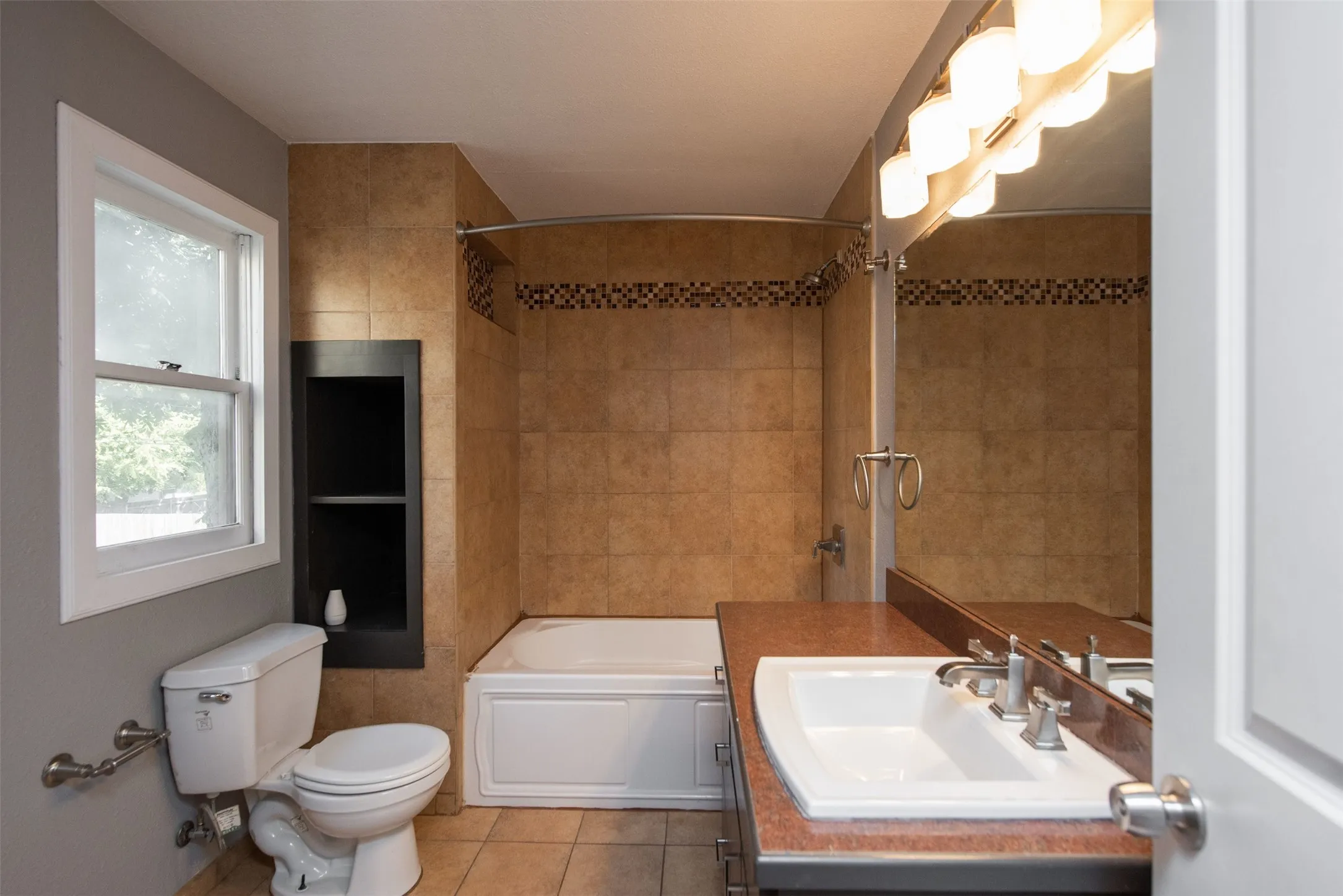 Full bathroom with vanity, tile walls, tiled shower / bath, toilet, and tile patterned flooring