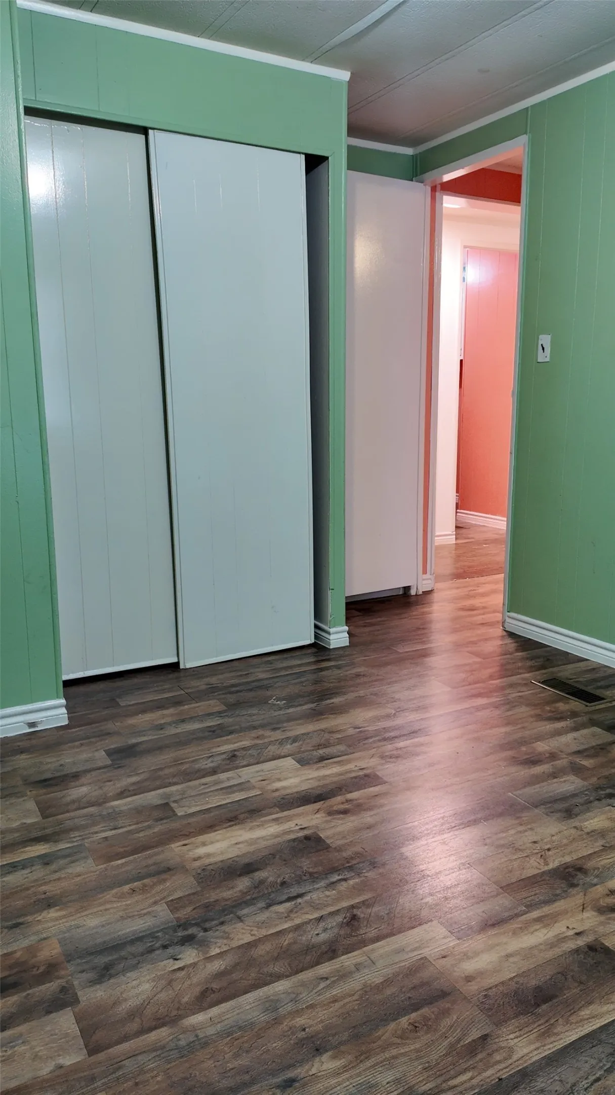 Wood-finish flooring throughout, paired with white trim and closet doors